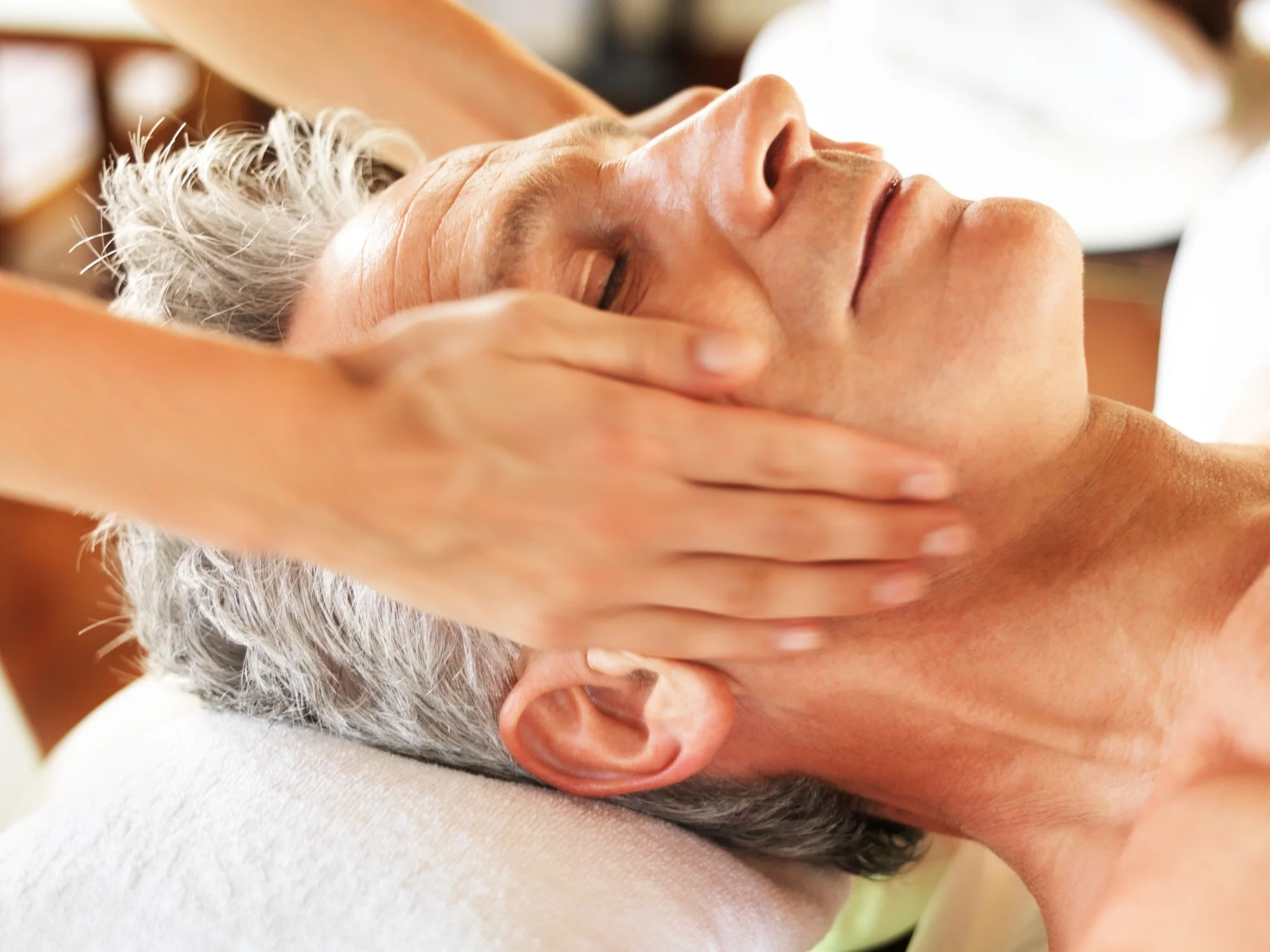 A person receiving a facial massage or treatment in a spa setting.