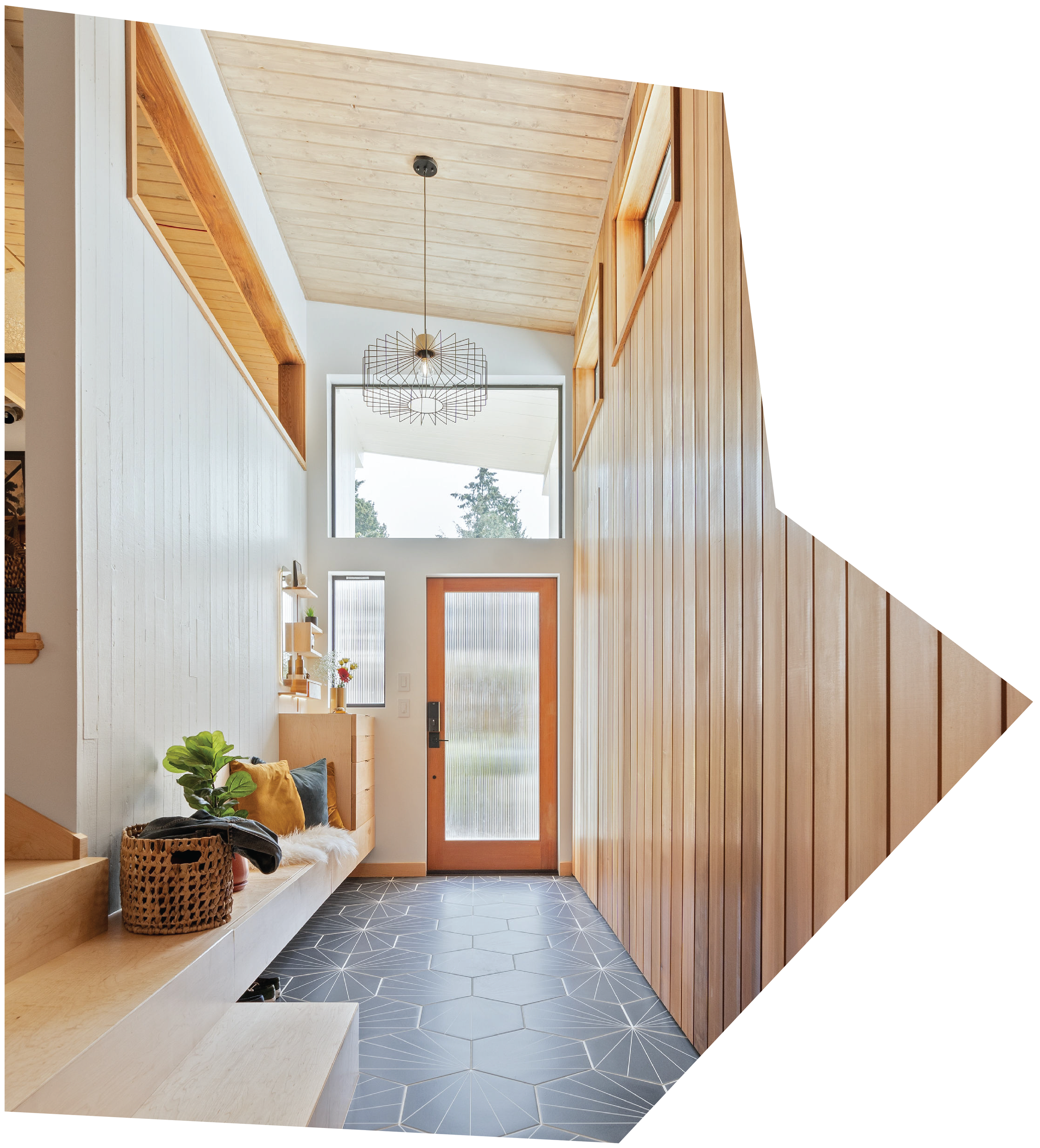 Bright entryway with wooden-paneled walls, a front door with a frosted glass panel, a built-in bench with pillows, and large windows letting in natural light.