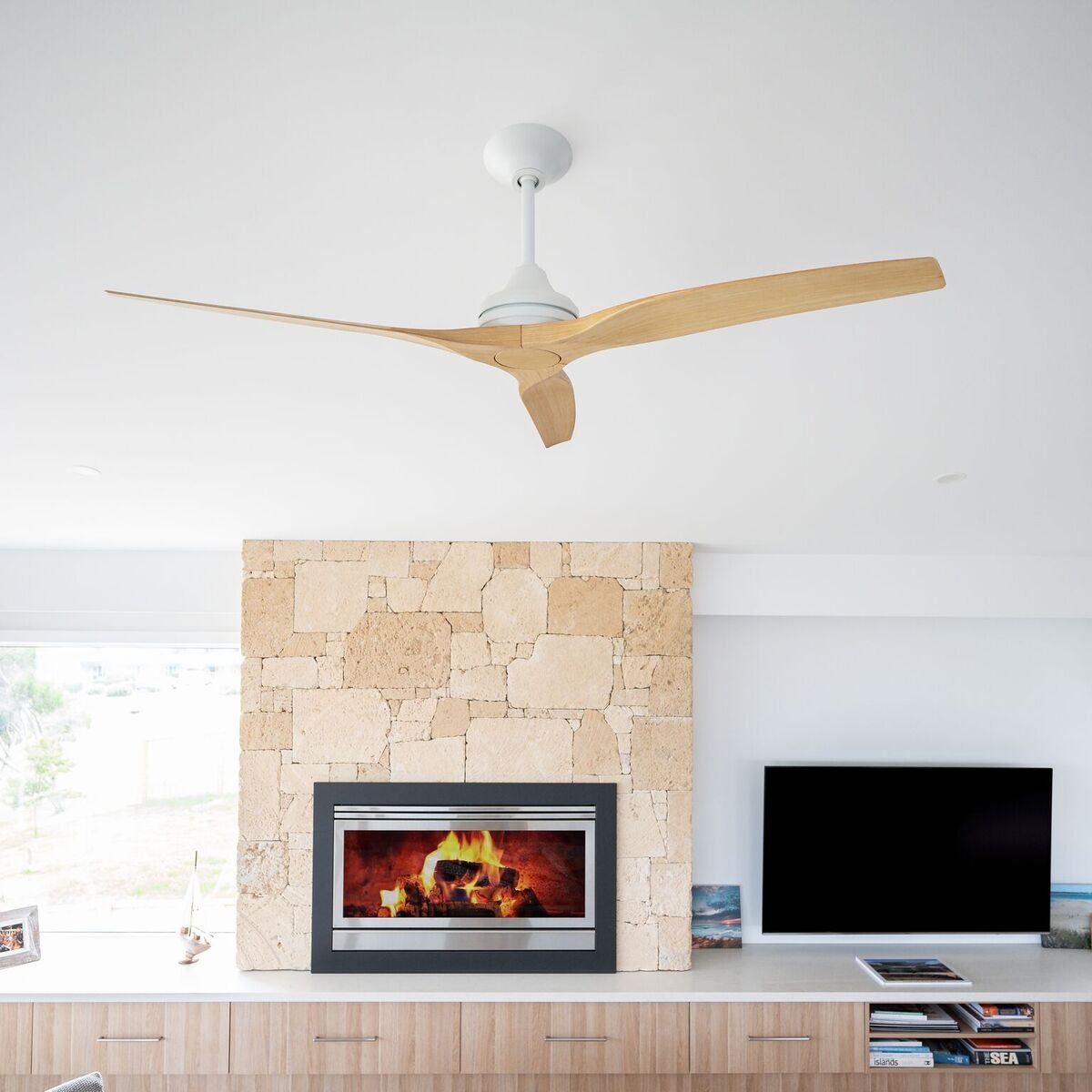 Living room ceiling with modern wooden ceiling fan, stone fireplace, and a flat-screen TV.