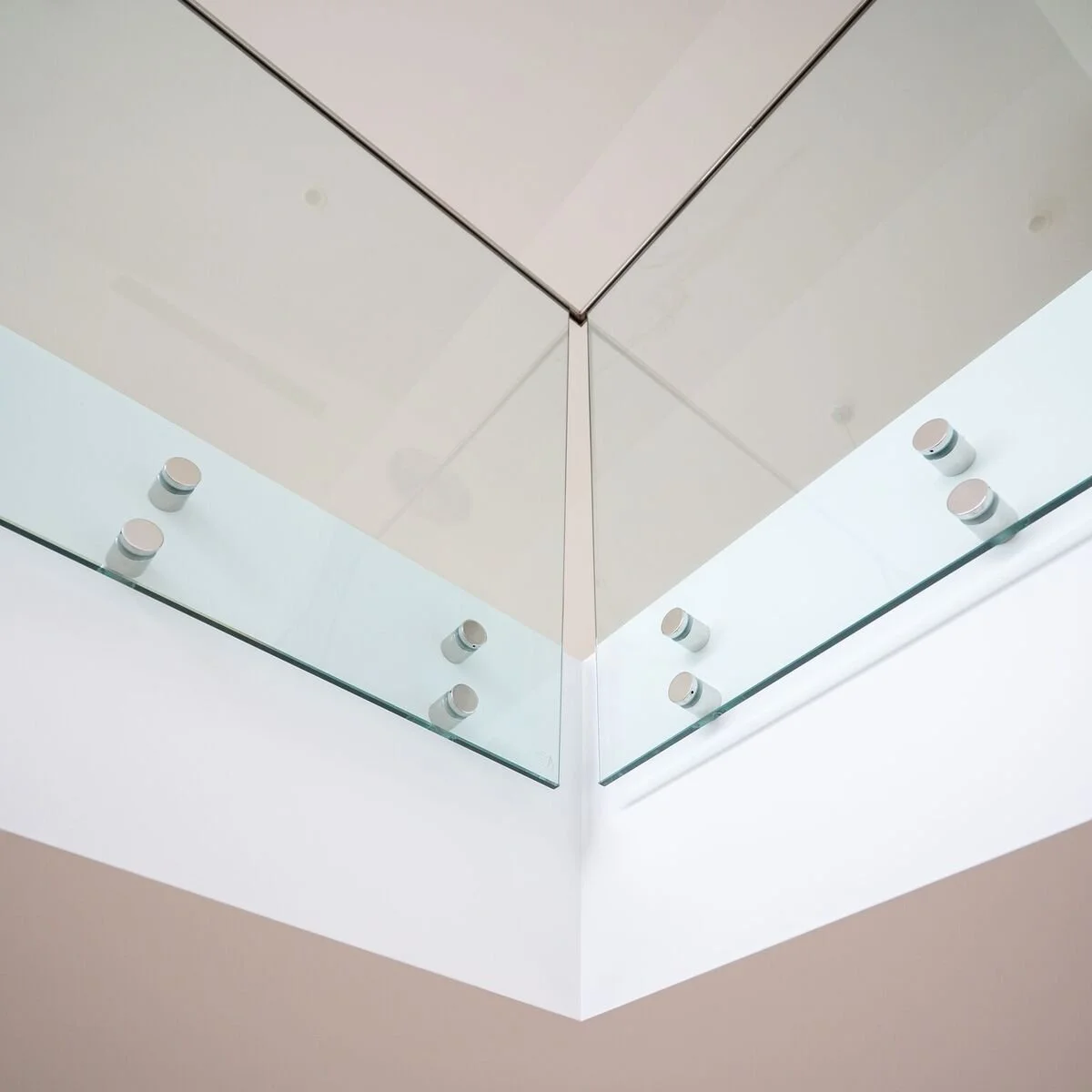 Close-up of a corner ceiling with recessed lighting and glass panels.