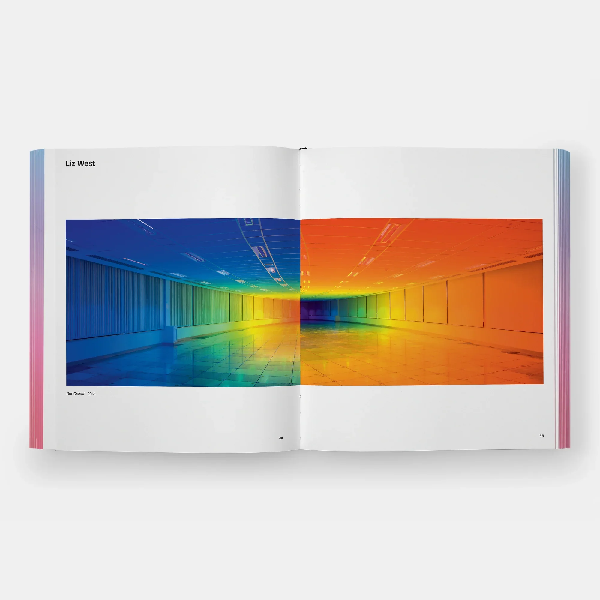 Rainbow Dreams Book by Olga Rei and Valentine Uhovski. Phaidon.  Open book showing a double-page photograph of an indoor corridor with different color schemes: left side in cool blue and green shades, right side in warm orange and yellow shades.