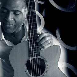 A man holding a guitar with decorative rings around him, in a black and white photo.