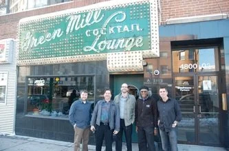 Four men standing outside Green Mill Cocktail Lounge, a bar with a green sign and large windows, at 4800.