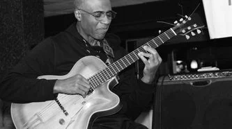 A man playing an acoustic guitar indoors.
