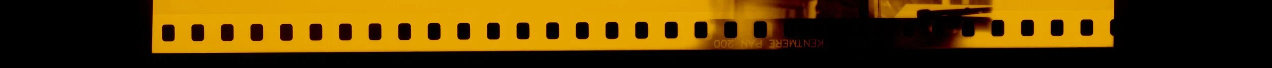 Close-up of a 35mm film strip with a yellow border and perforations, showing the film's perforated edges.