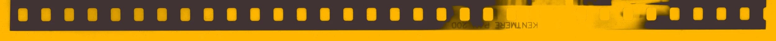 Close-up of a yellow film strip with sprocket holes along the edges.