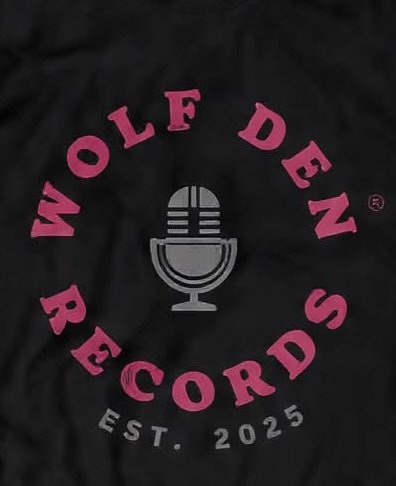 Black shirt with pink text that reads 'WOLF DEN RECORDS' surrounding a gray vintage microphone graphic, and smaller text that says 'EST. 2025'.