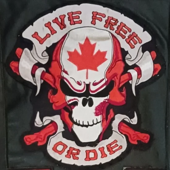 A skull with a red maple leaf on its forehead, flanked by two red guns, and surrounded by a banner that reads "Live Free or Die."