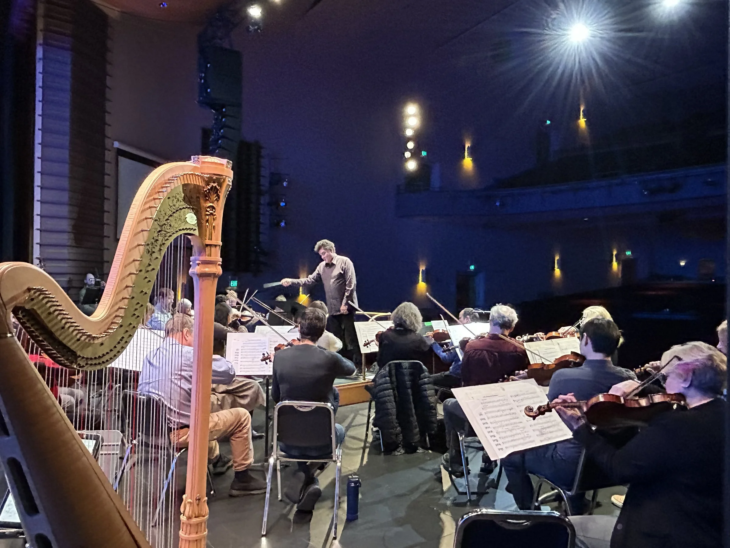 The GBS harpist and orchestra rehearse on stage at the Klein Memorial Auditorium