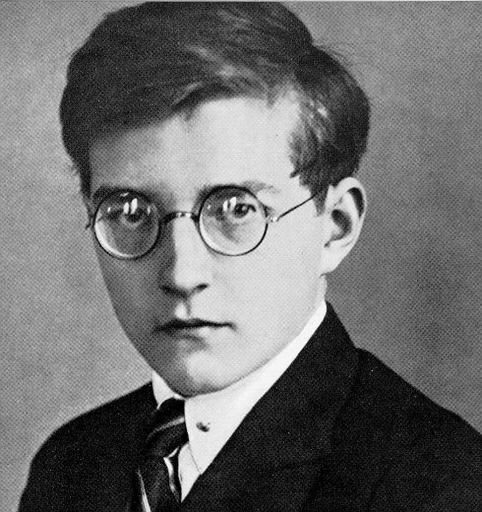 Black-and-white portrait of a young man wearing glasses, a suit, and a tie.