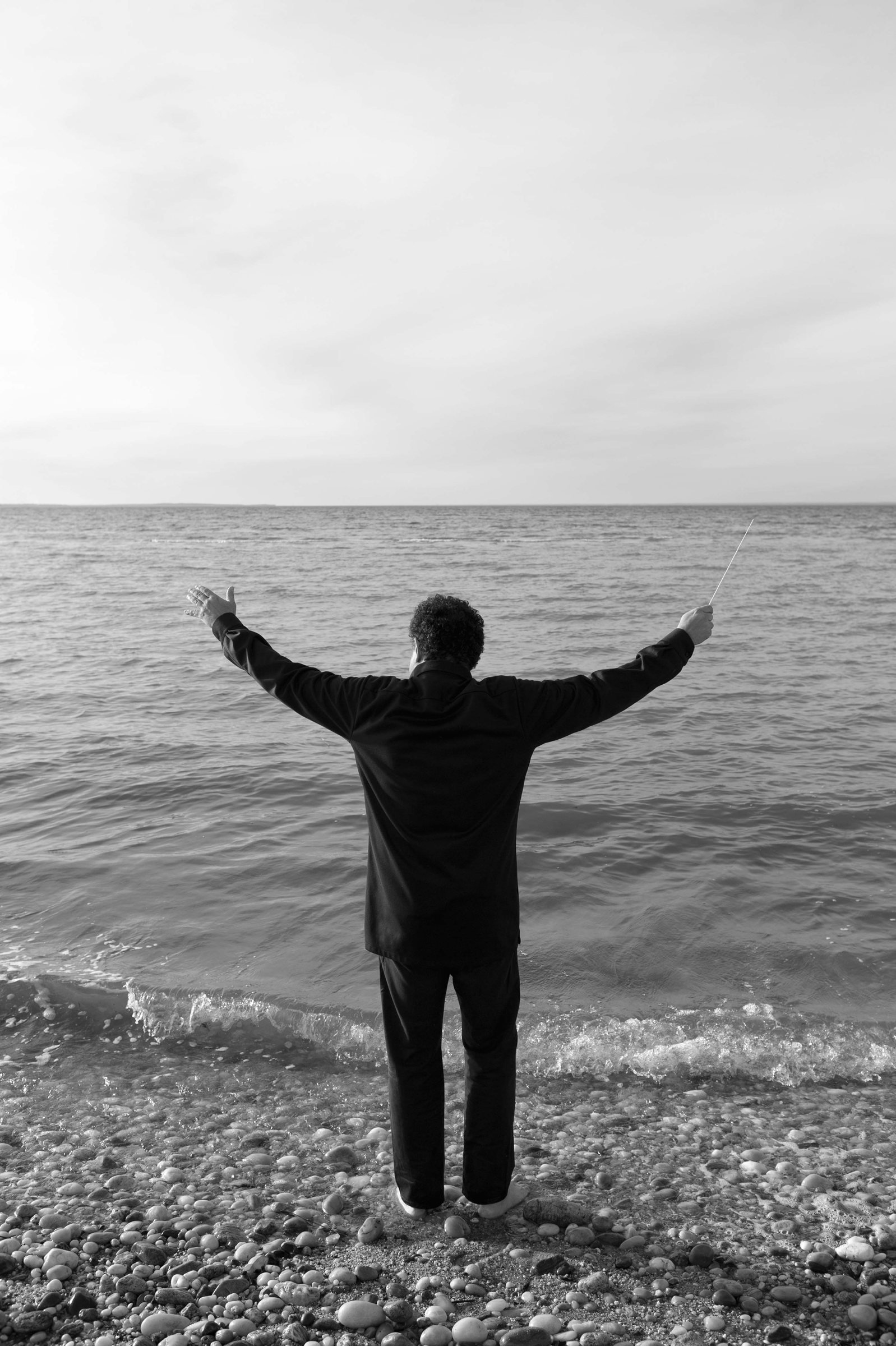 Music Director Eduardo Leandro at the water's edge, arms raised