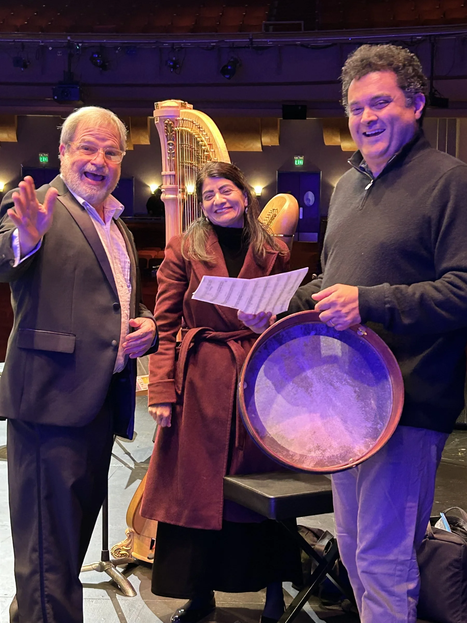 GBS musicians share a laugh backstage, one holding a frame drum