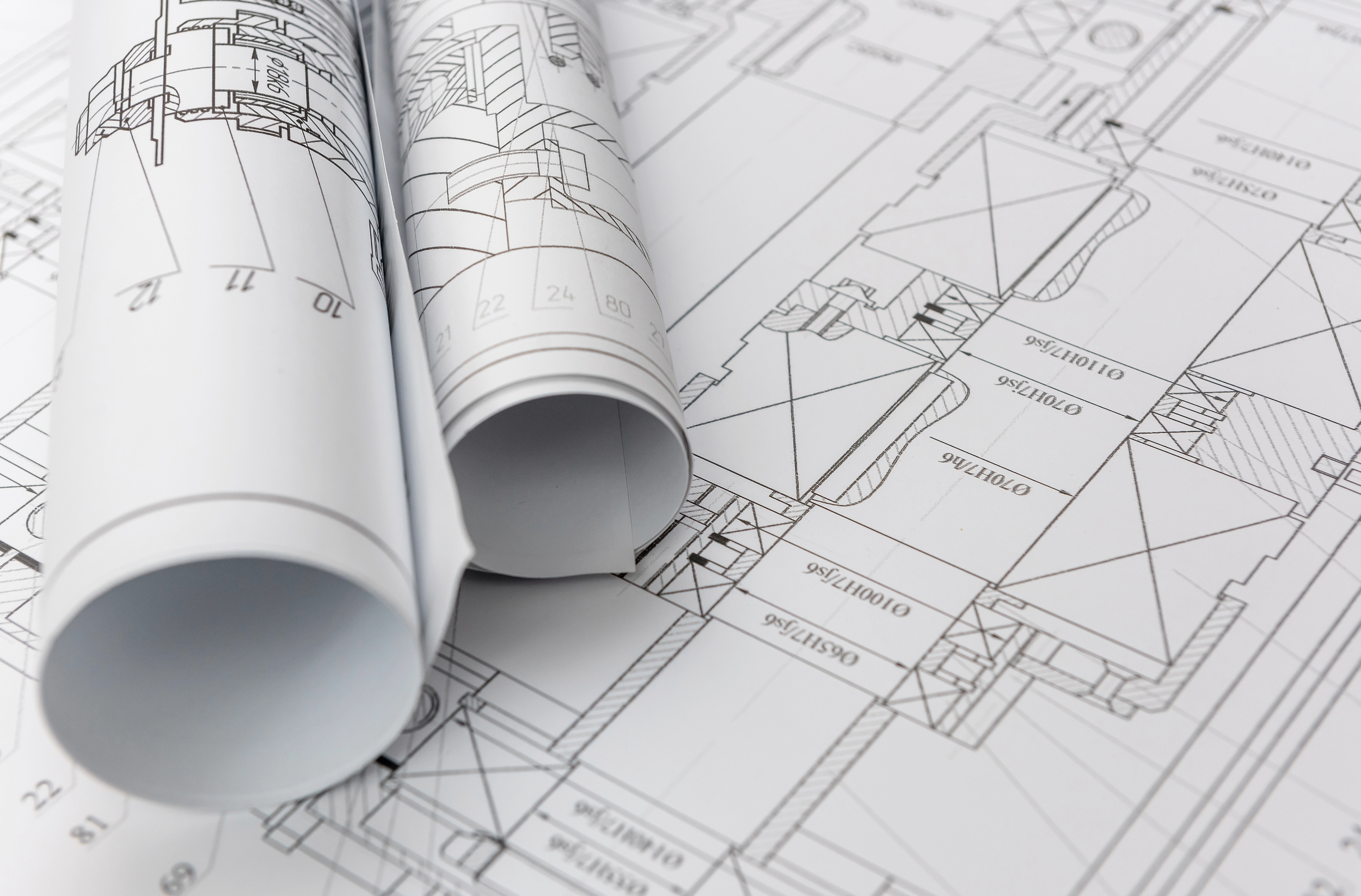 Architectural blueprints with rolled-up plans on top. Construction Consulting Owners Representation