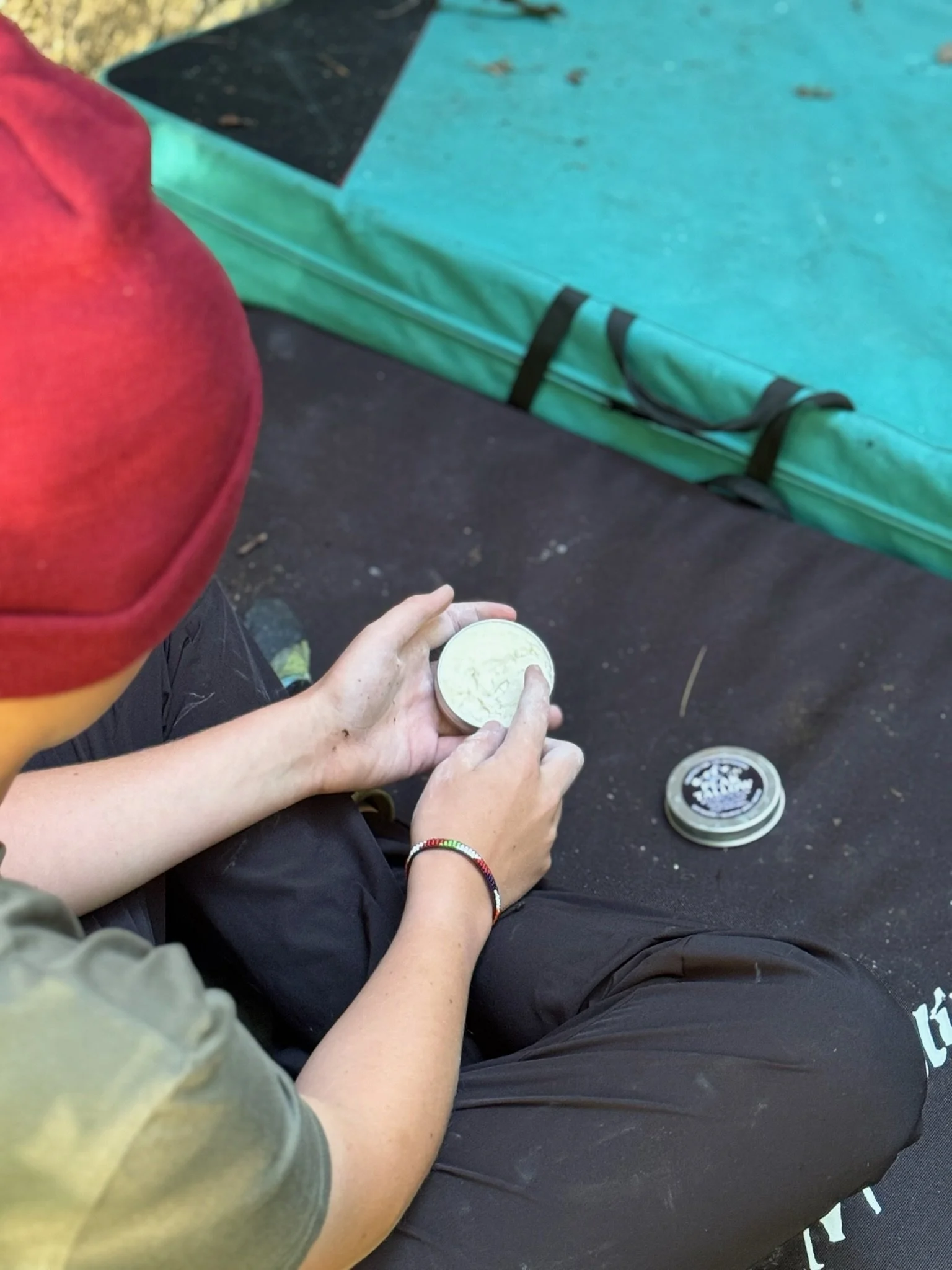 Grass fed tallow balm applying to climber in the woods. All natural restorative balm