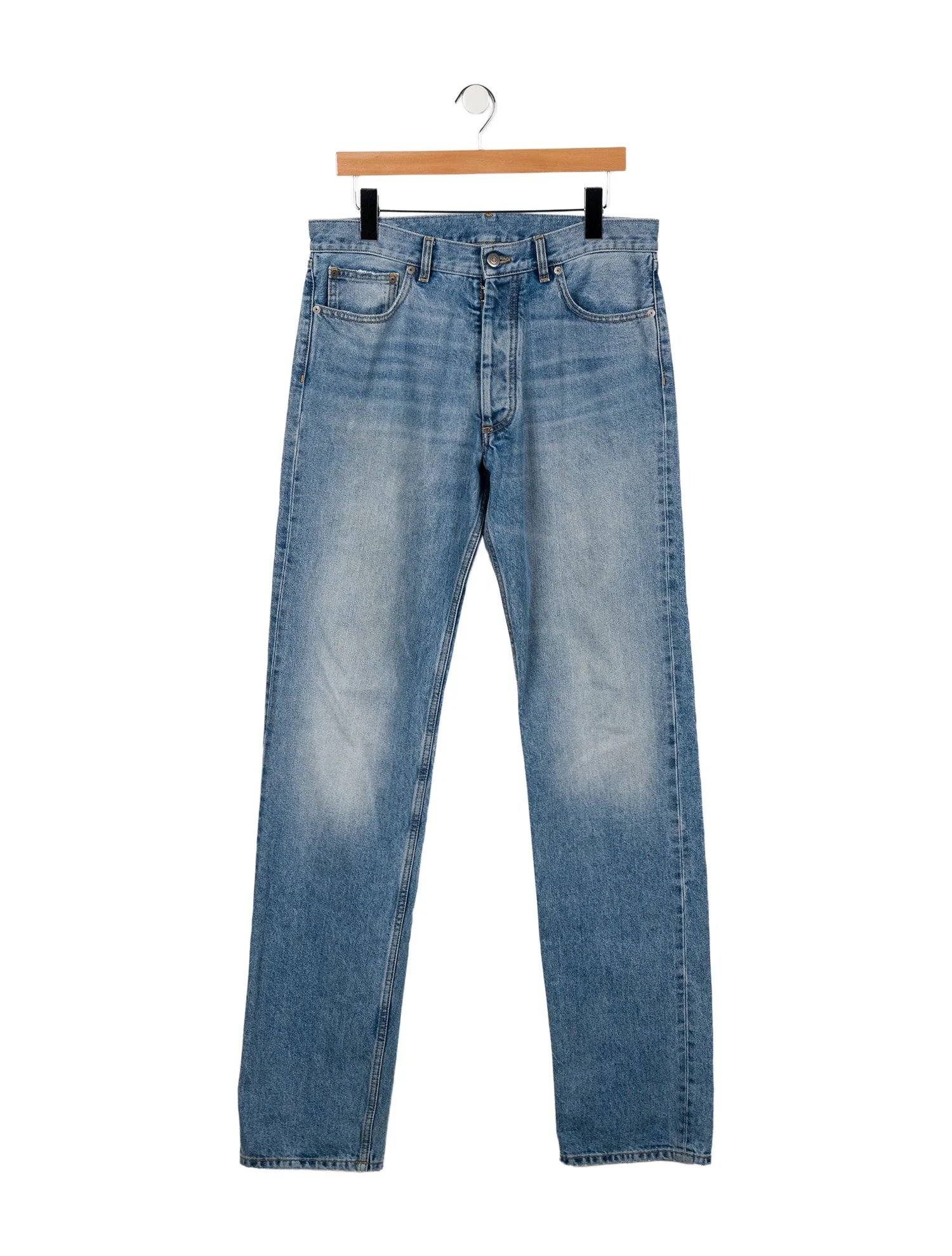 A pair of blue denim jeans hanging on a hanger against a white background.