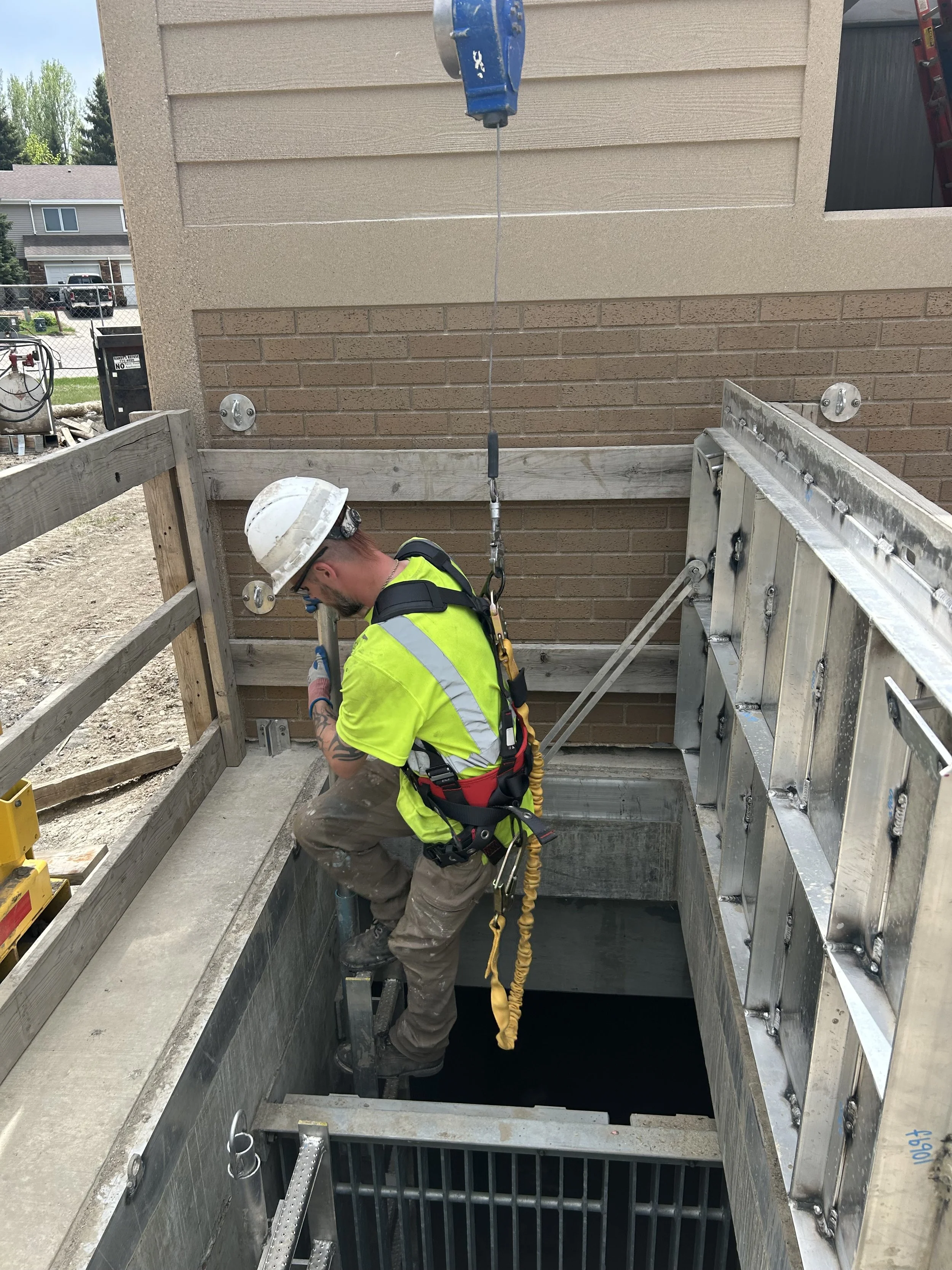 Construction worker with safety gear working near an open elevator shaft.