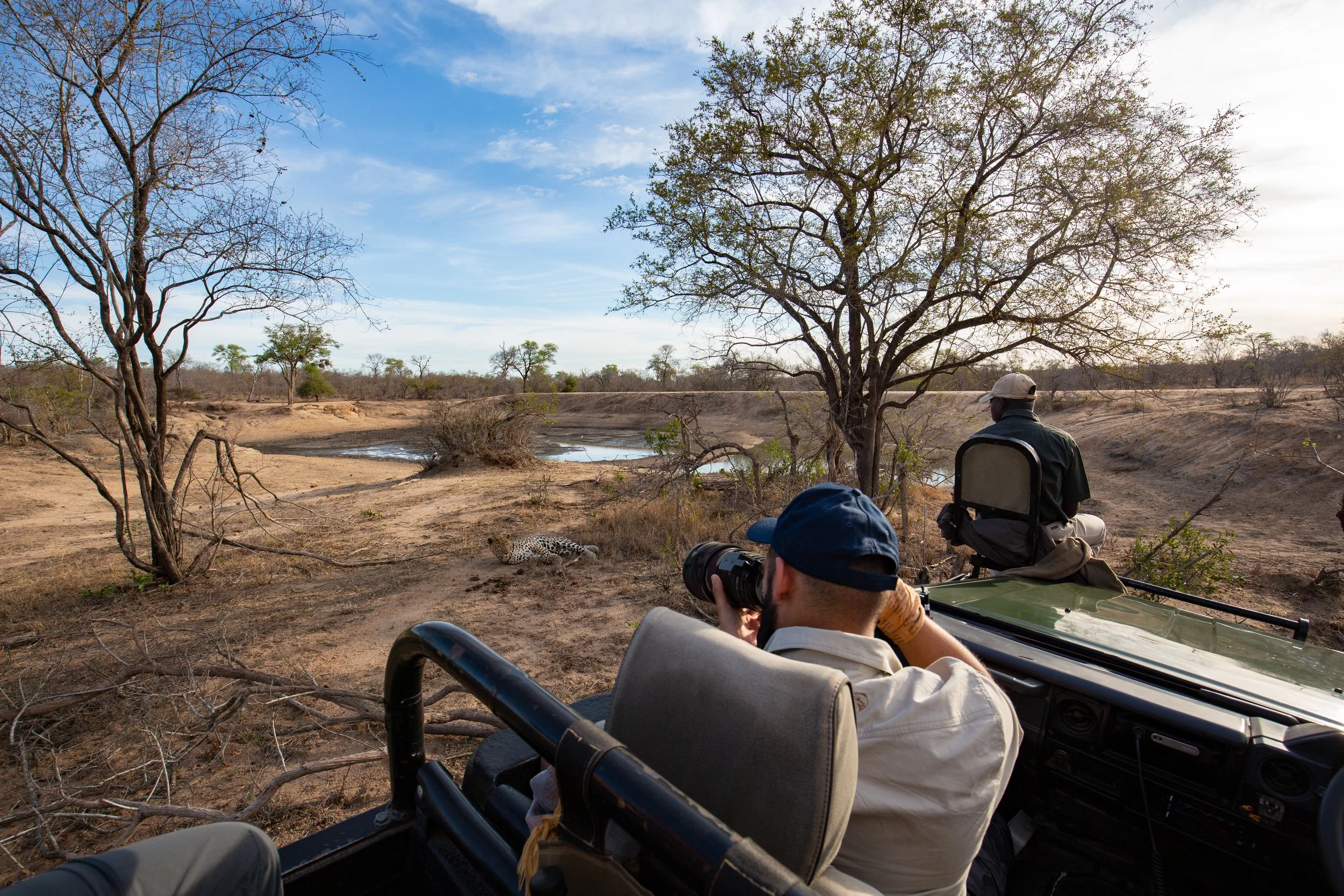 Safari guest photographing wildlife with a large camera from an open safari vehicle in the Sabi Sands, South Africa