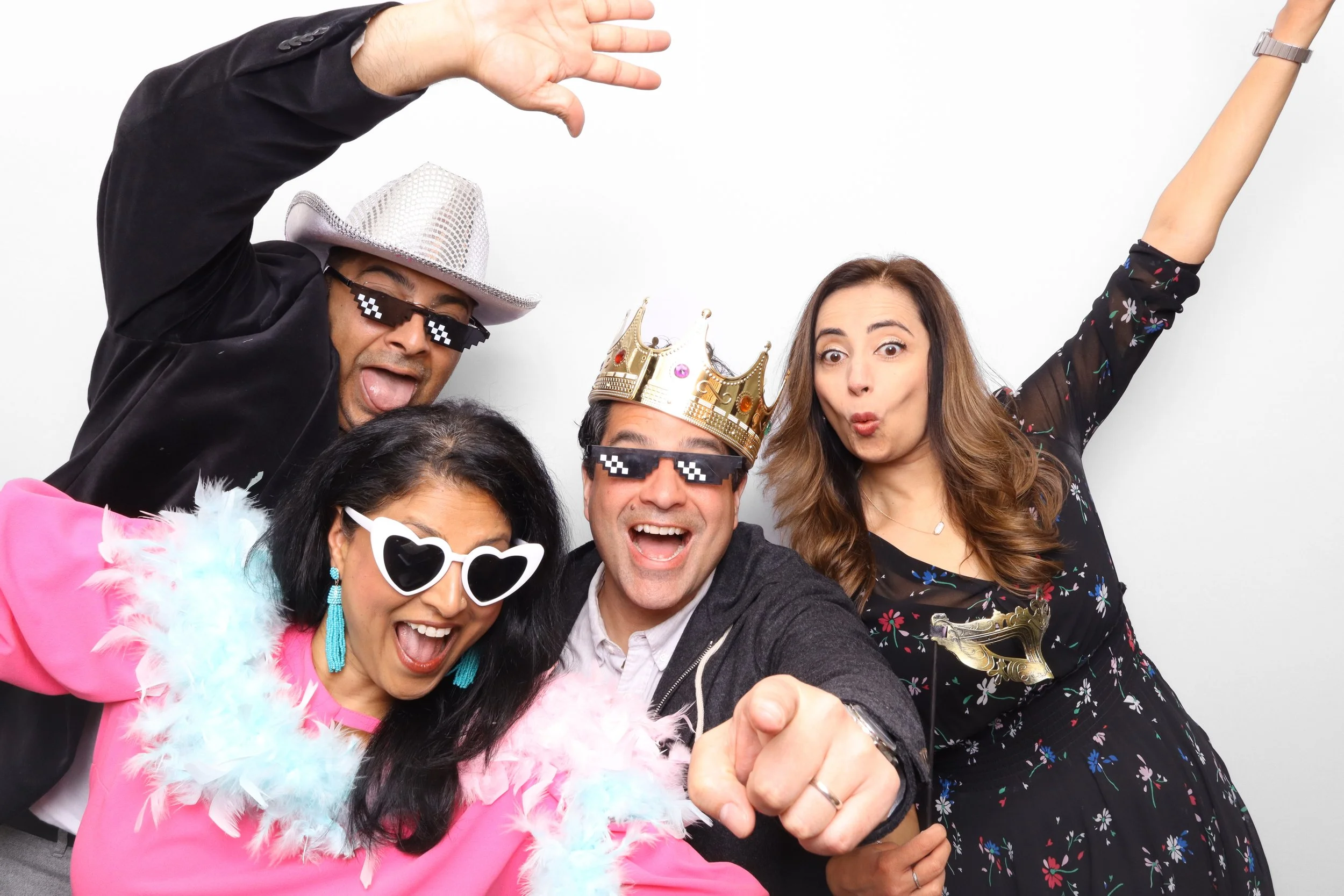 Group of five diverse people celebrating together, wearing fun accessories like crowns, sunglasses, and feather boas, with expressions of happiness and excitement.