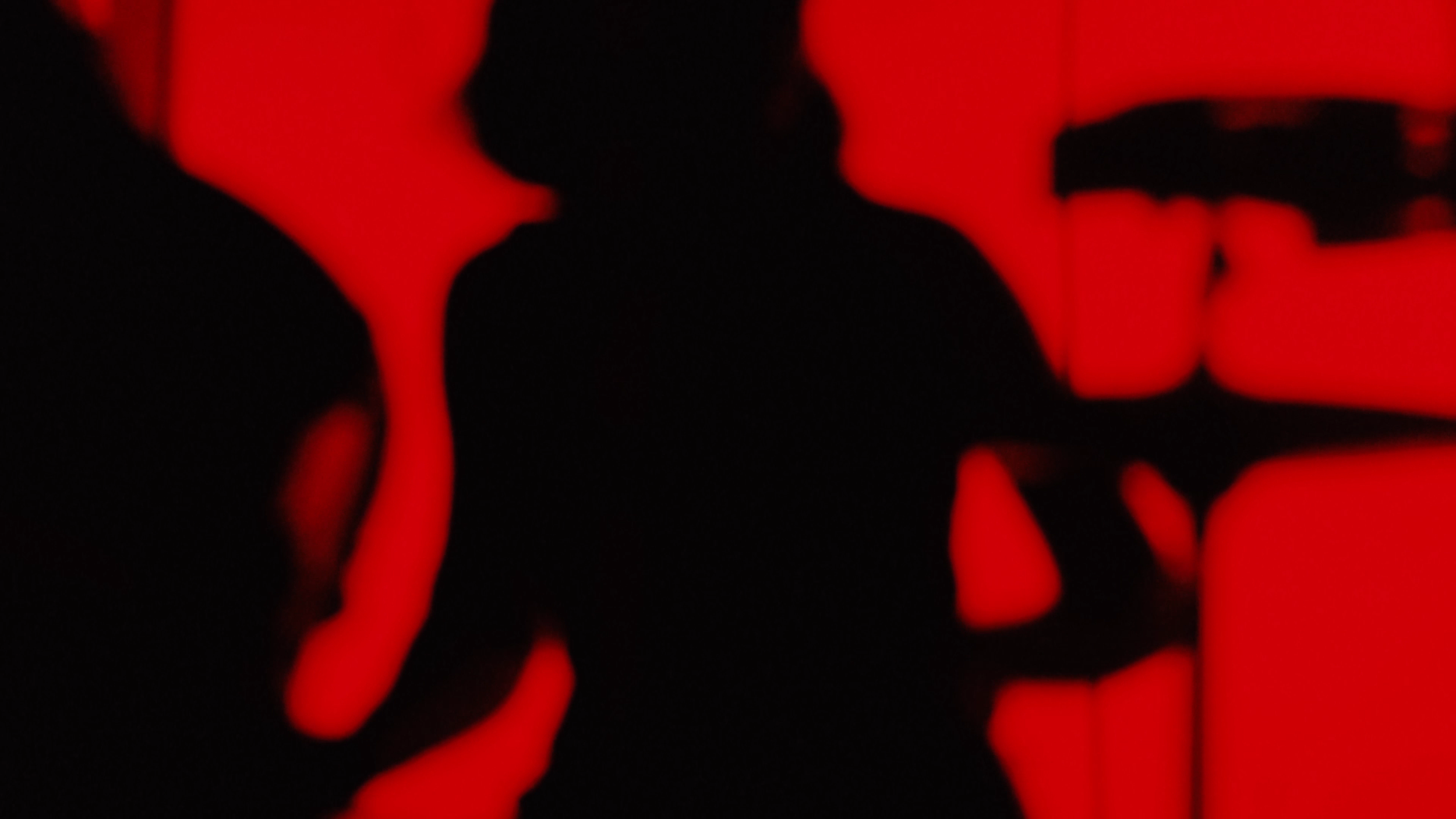 Silhouettes of three people against a red background, appearing to be in a social setting.