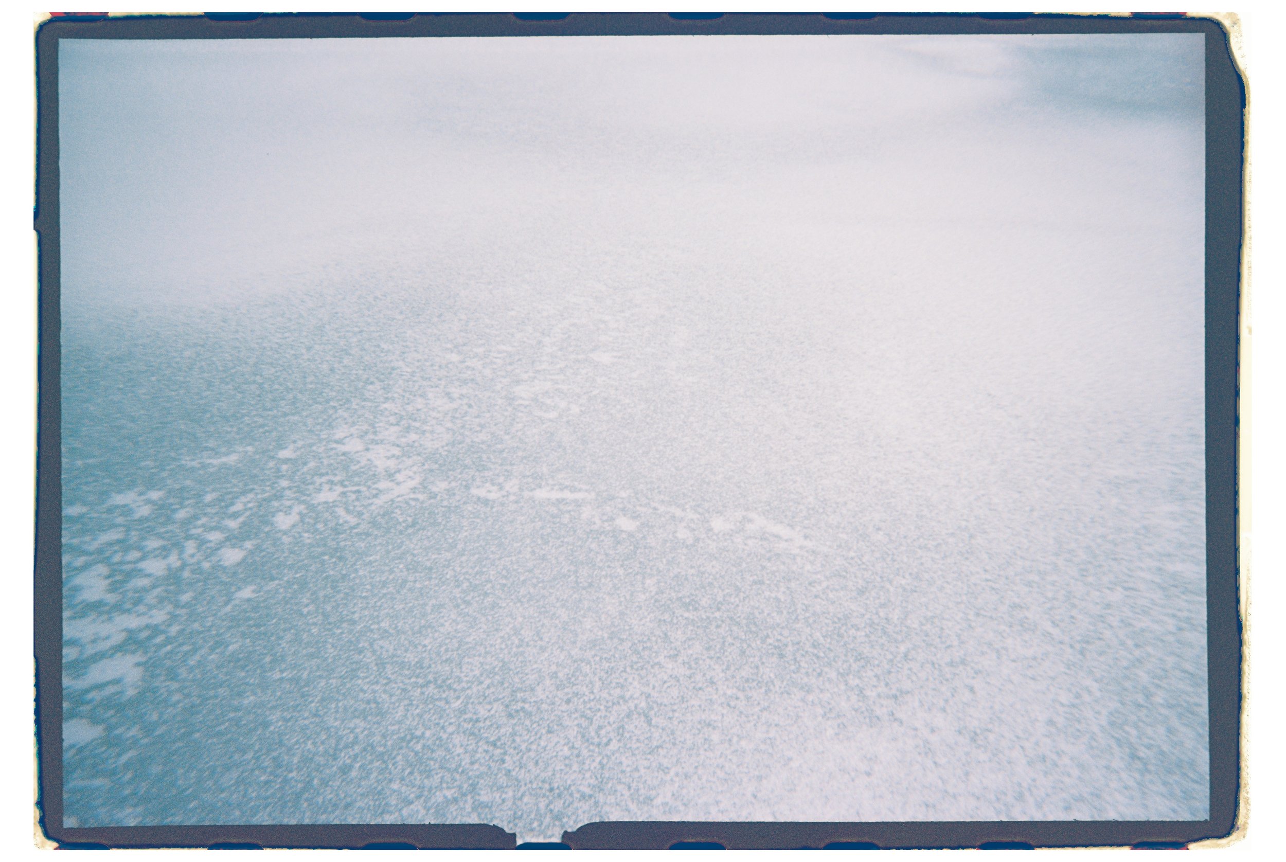 An open photo album with textured light blue pages and a dark blue border.