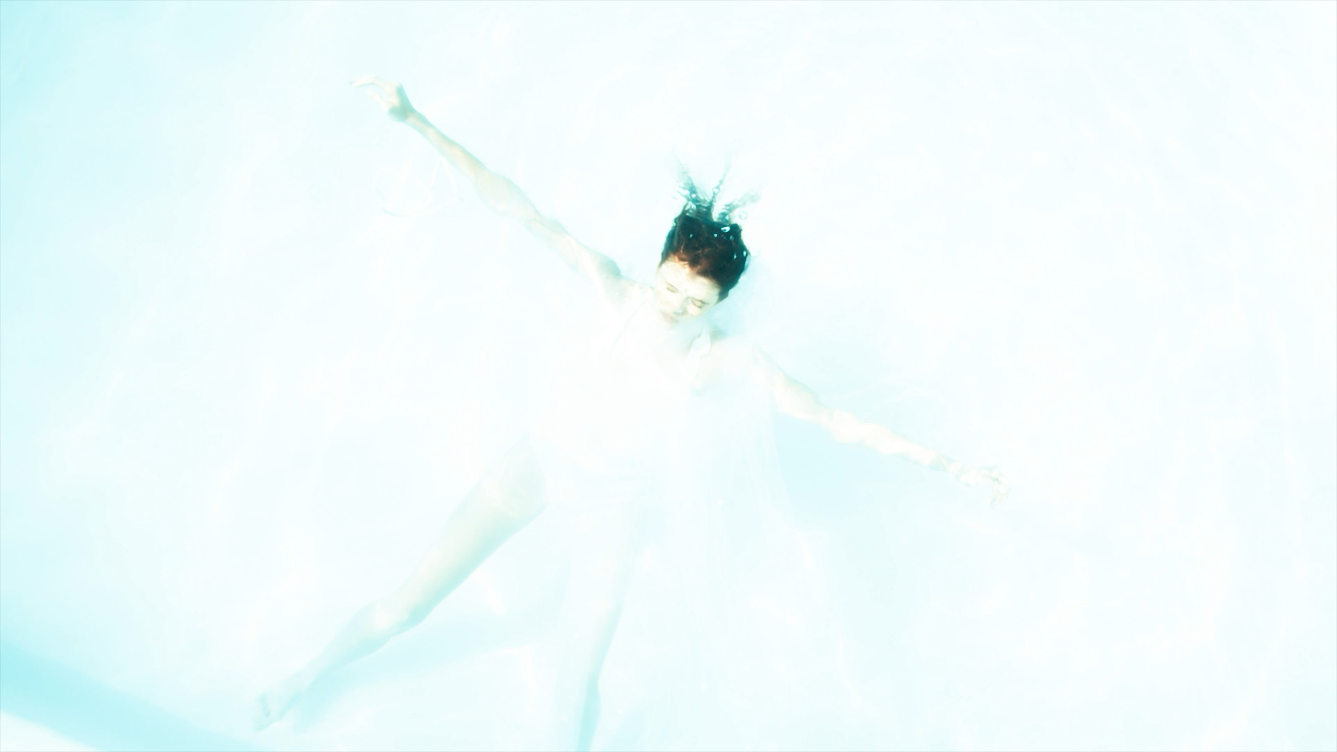 A woman swimming underwater with her arms and legs extended.