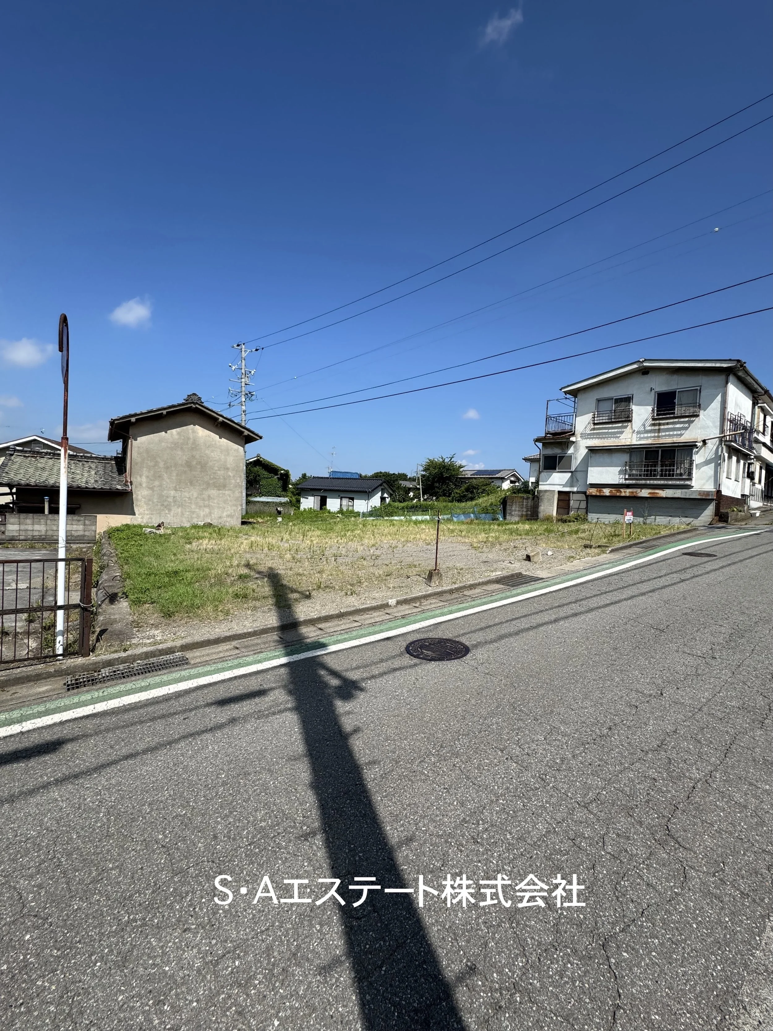 屋外にある温室と木製のパーゴラ、テーブルと椅子、砂利や落ち葉が散らばる土の地面。