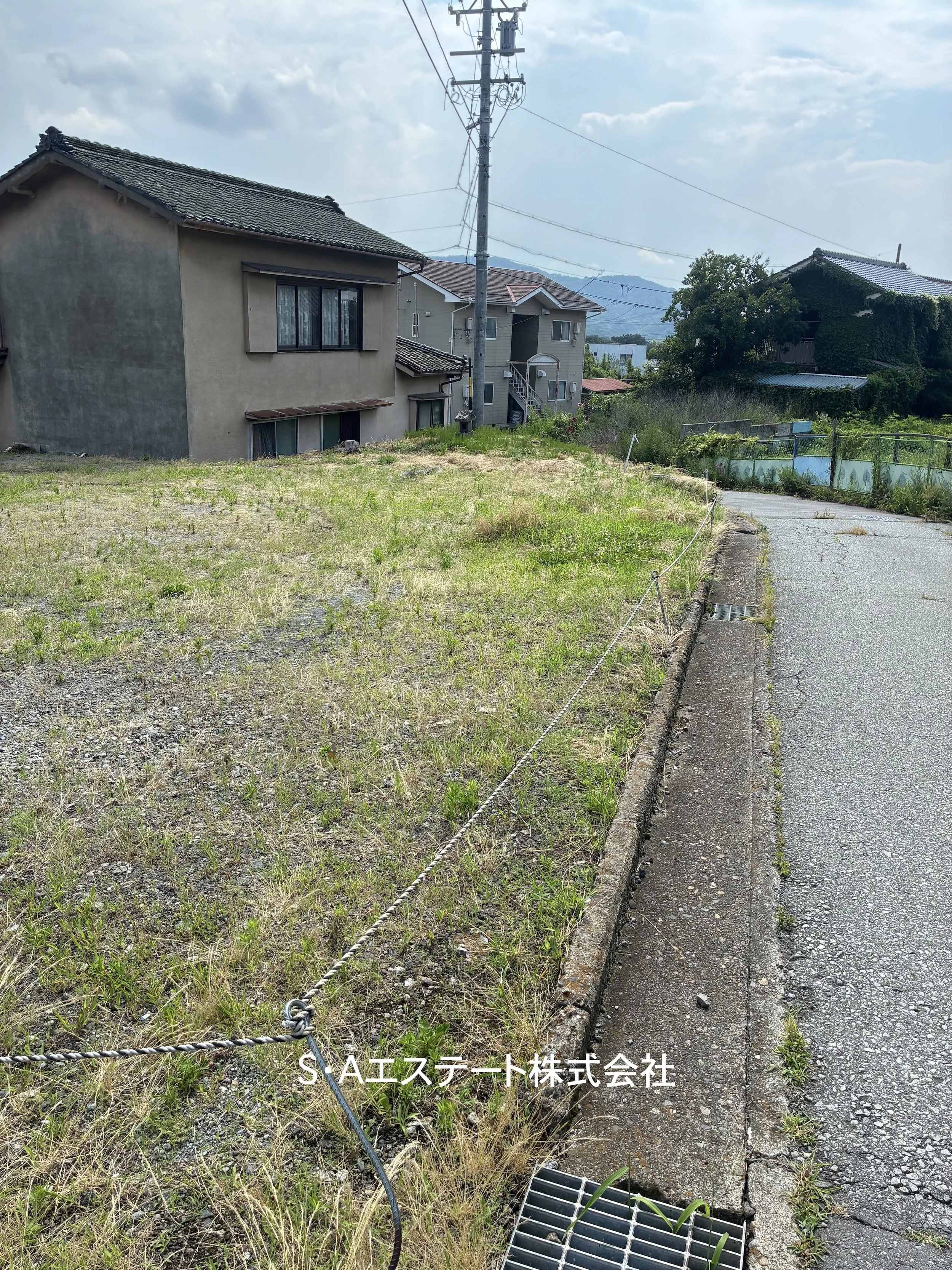 室内の風景、木製の仕切りとテーブル、黄色いサンダル、配管と広告ポスターが壁に貼ってある。