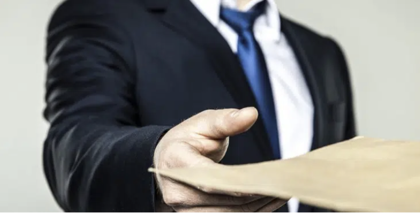 Businessperson in suit handing a document to someone