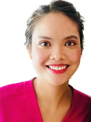 Close-up of a woman with dark hair, smiling, wearing a pink top, against a white background.