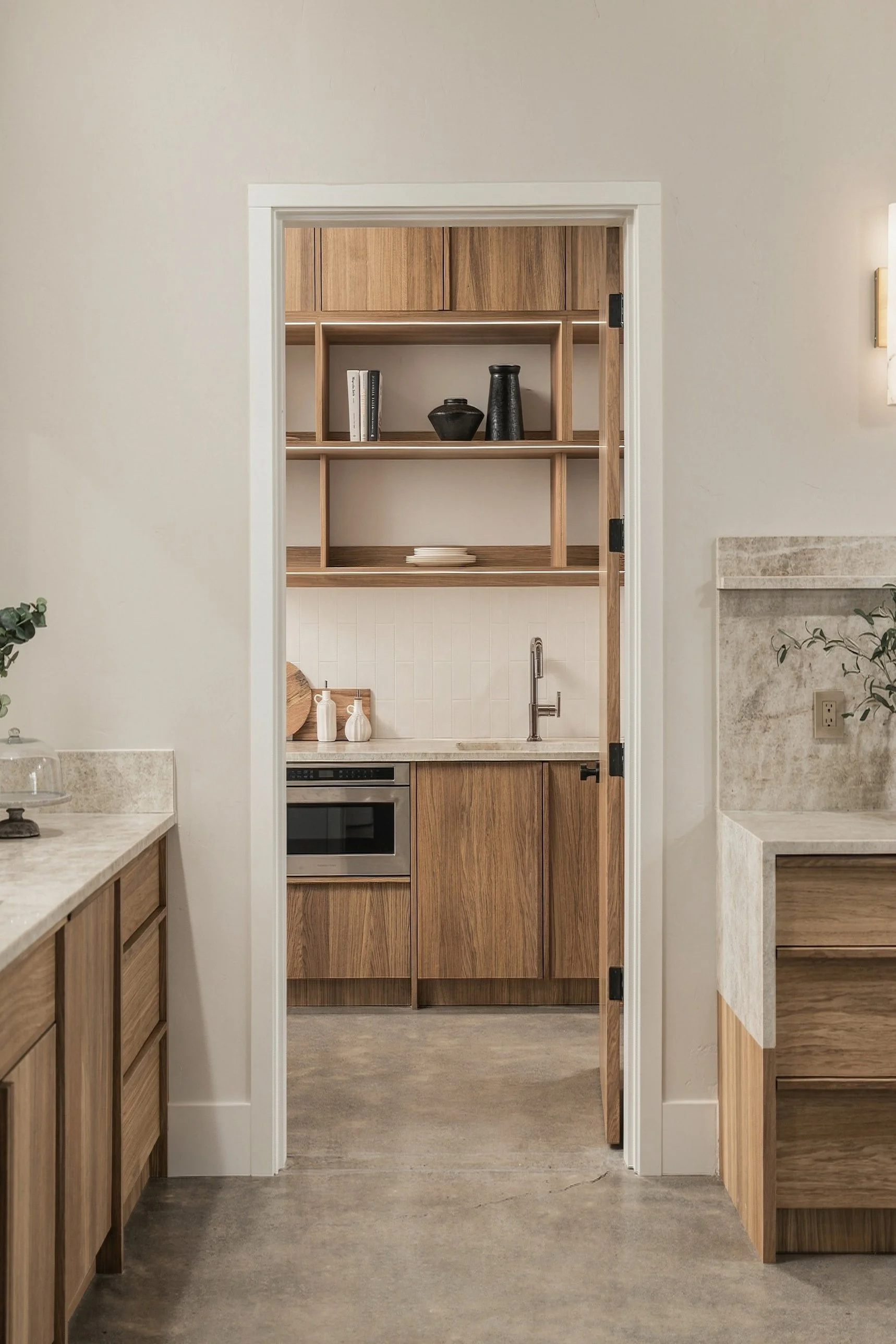 Scullery with oak cabinets and lit open shelves, seen through a doorway