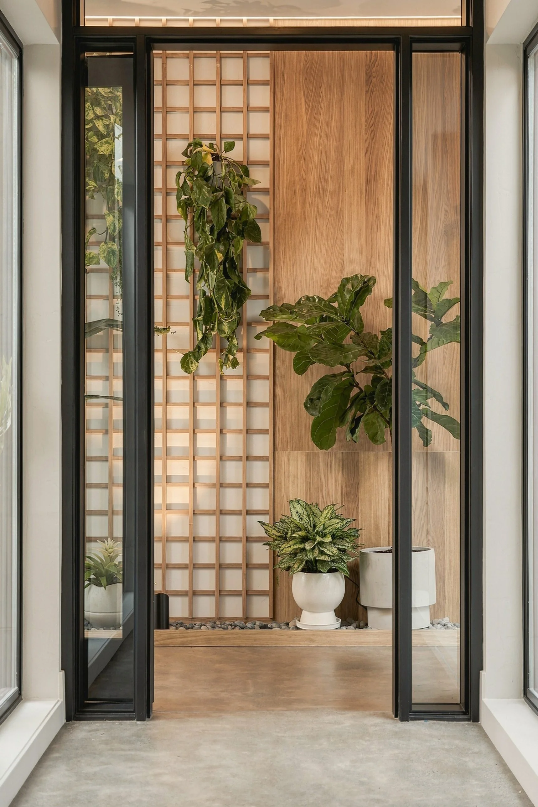 Glass-walled atrium with an oak lattice screen and indoor plants