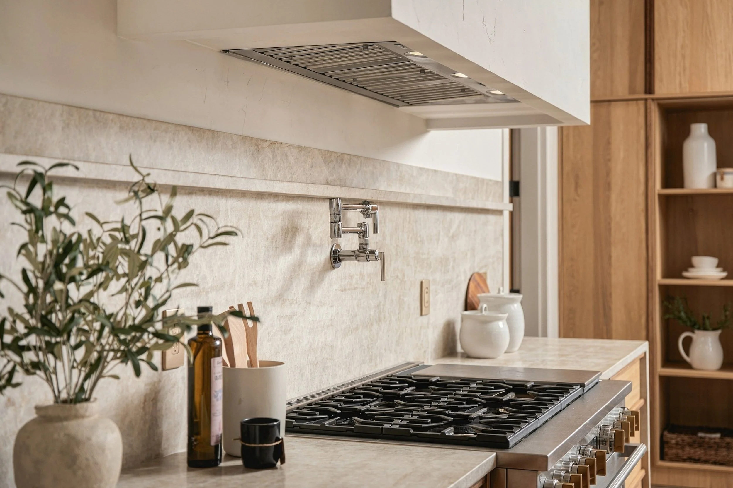 Range with a pot filler set into a full-height stone backsplash