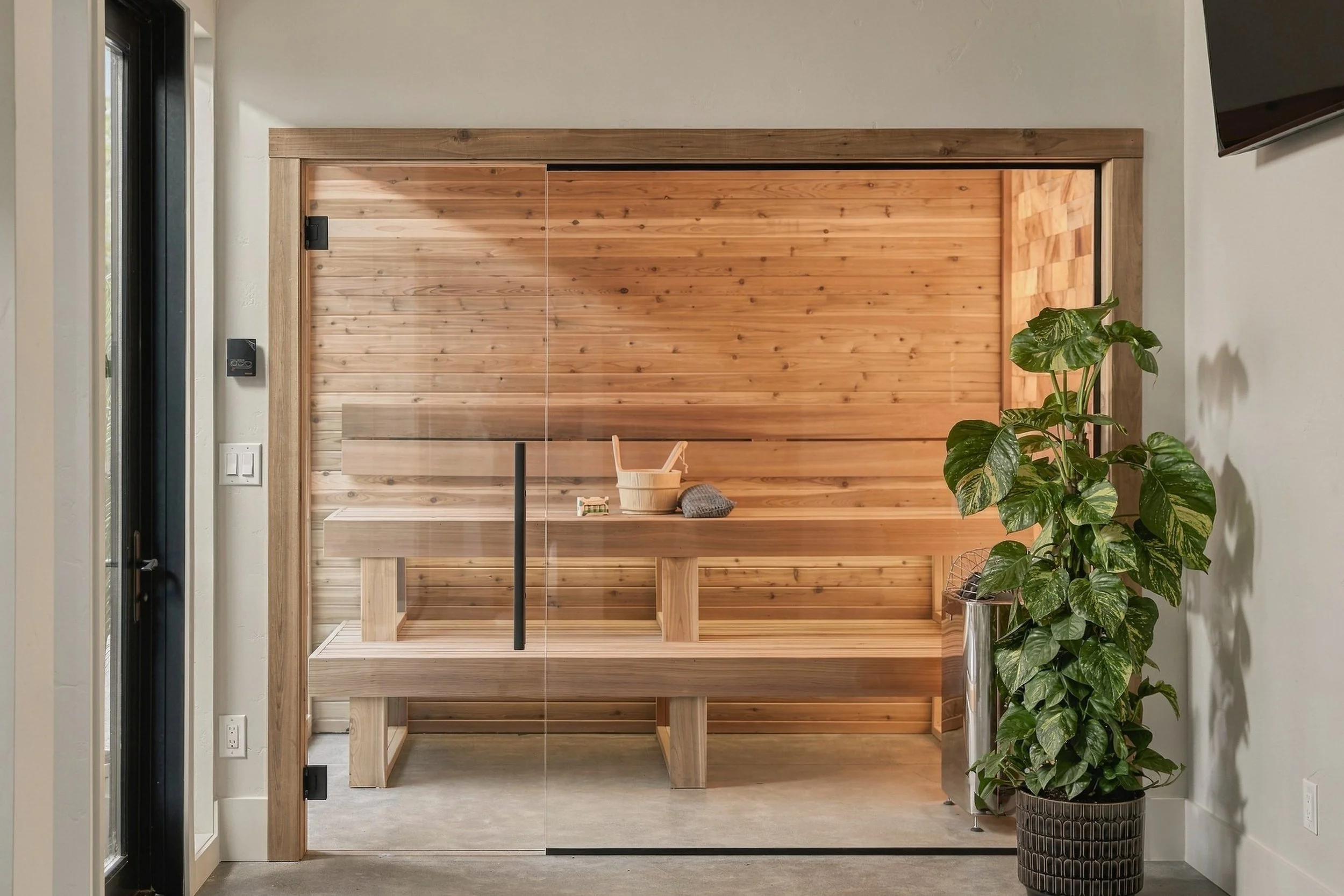 Cedar sauna behind a frameless glass front