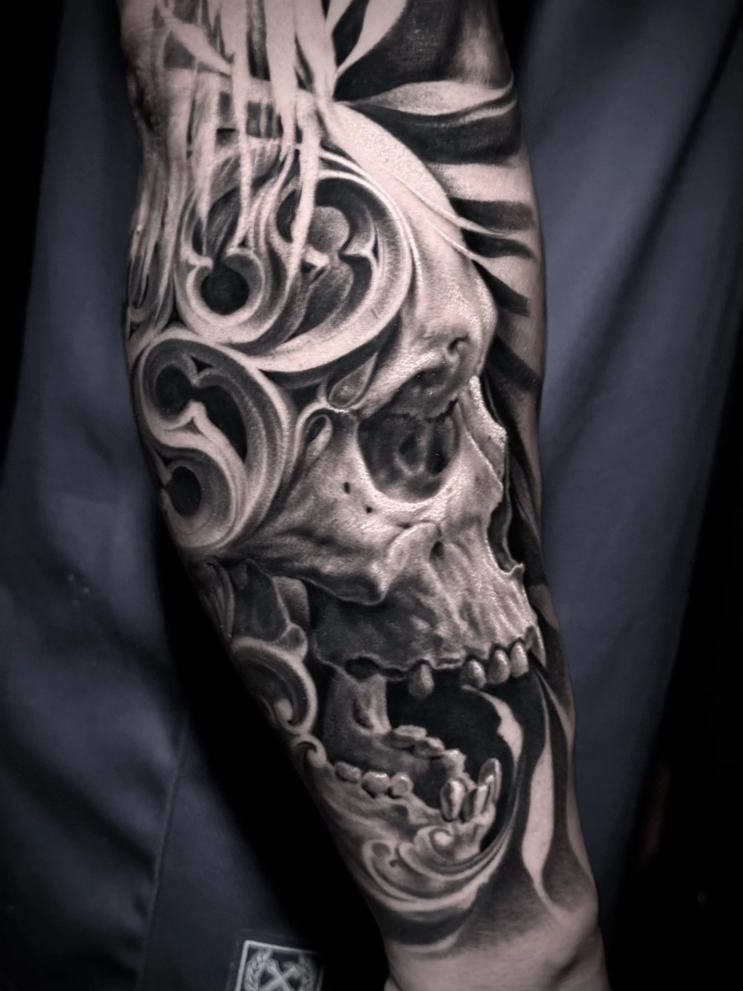 Realistic Tattoo of a skull with decorative swirls on arm.  By Jhon Gutti. In Los Angeles Area, at Outer Limits tattoo shop.