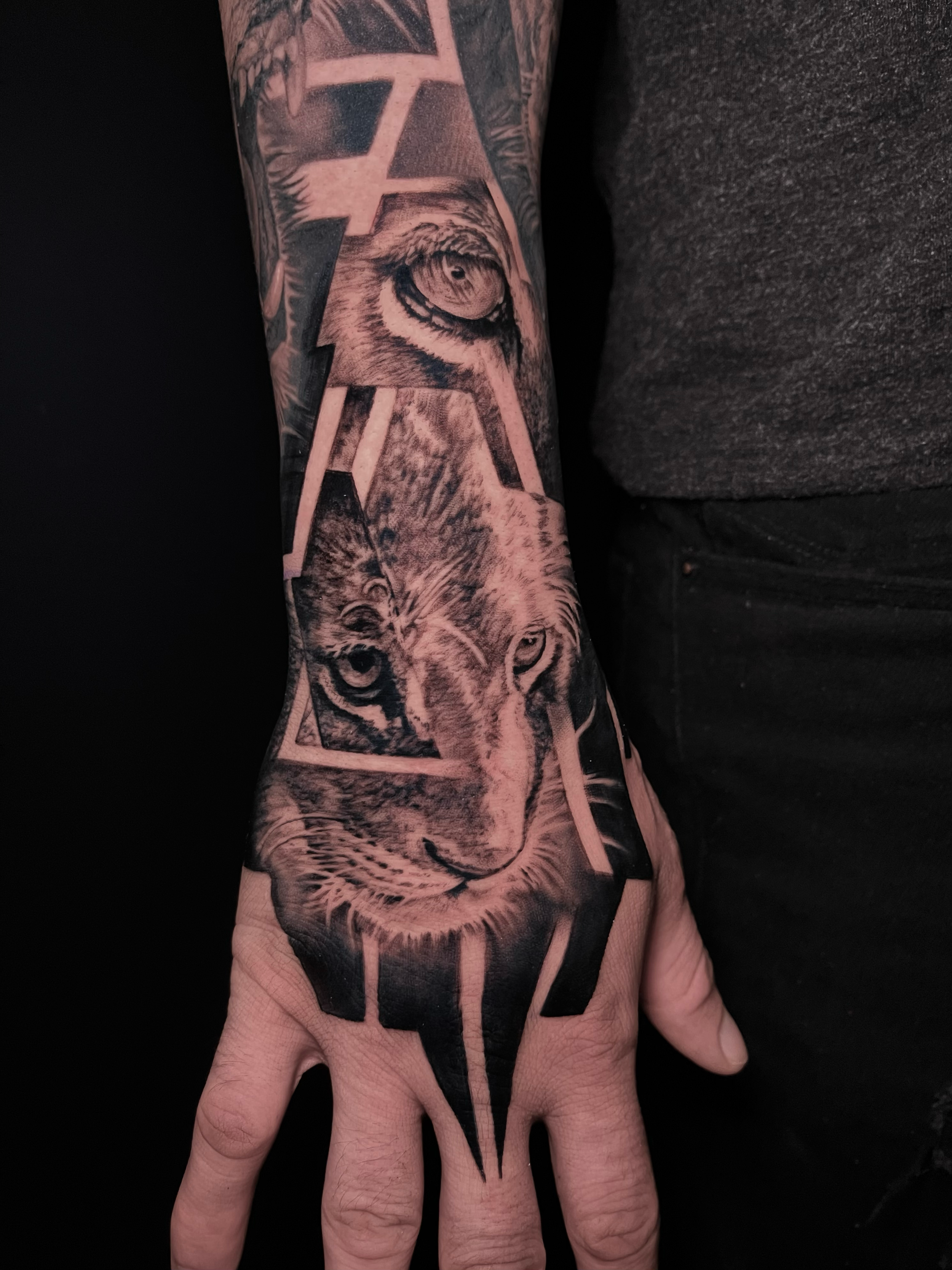 Innovative realistic black and grey tattoo lion cub with graphic design integration, hand tattoo In Los Angeles Area, at Outer Limits tattoo shop. by Jhon Gutti