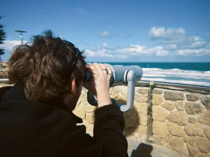 Person looking through a coin-operated telescope at the ocean view