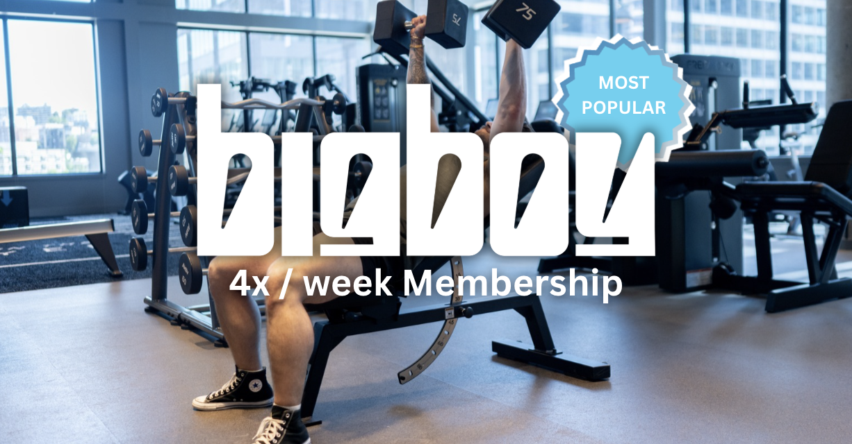 Person lifting dumbbells in a modern gym with large windows, exercise machines, and a city view outside.