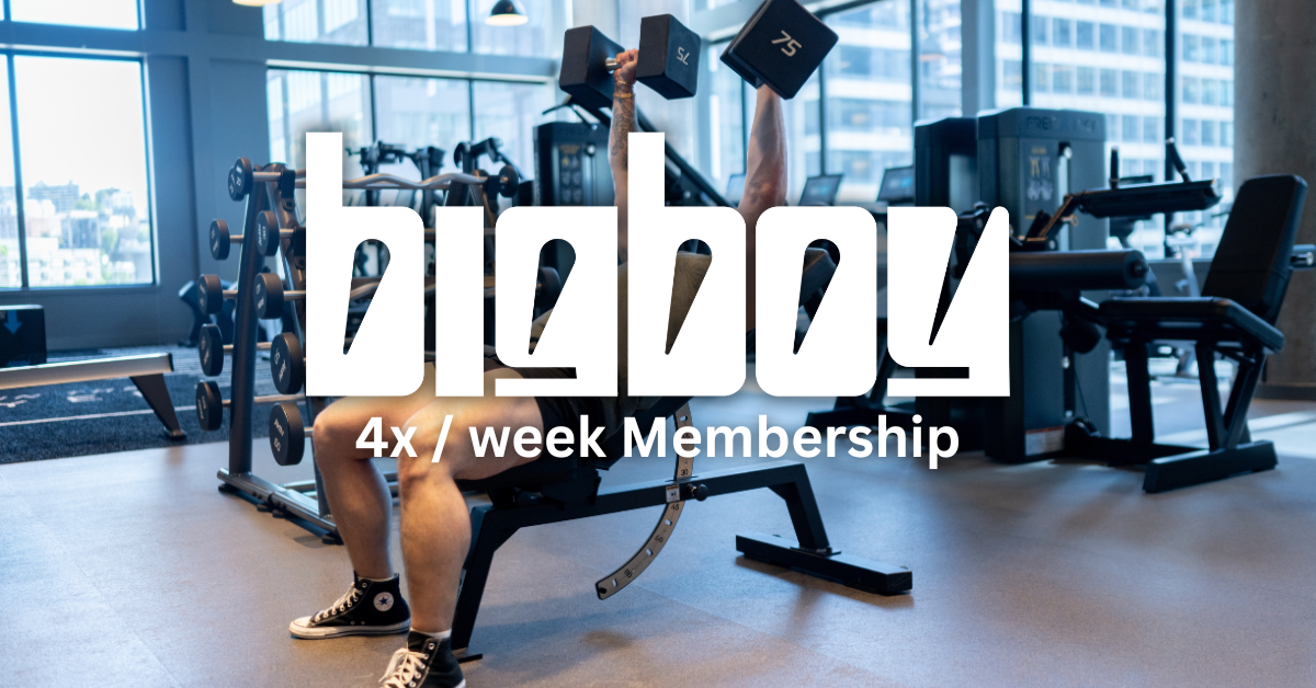 Person lifting dumbbells in a modern gym with large windows, exercise machines, and a city view outside.