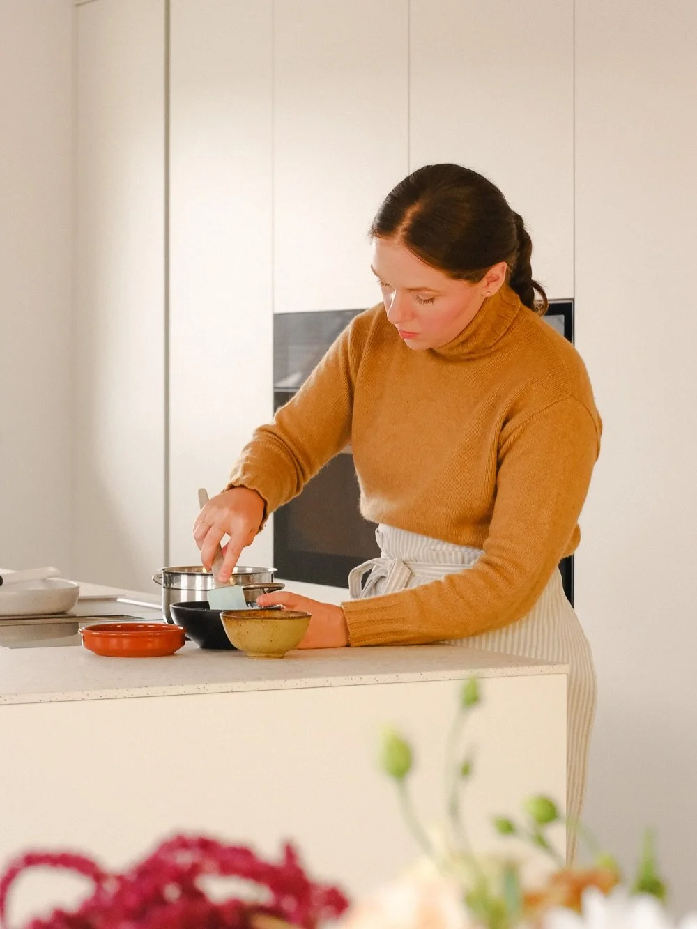 Da bi nevtralni zasnovi kuhinje dodali malce nepričakovane živahnosti, smo za notranjost omar izbrali mehko karamelno-oranžno barvo. Ta kontrastni barvni poudarek se razkrije &scaron;ele ob odprtju omaric in prostoru doda toplino, ne da bi poru&scaro