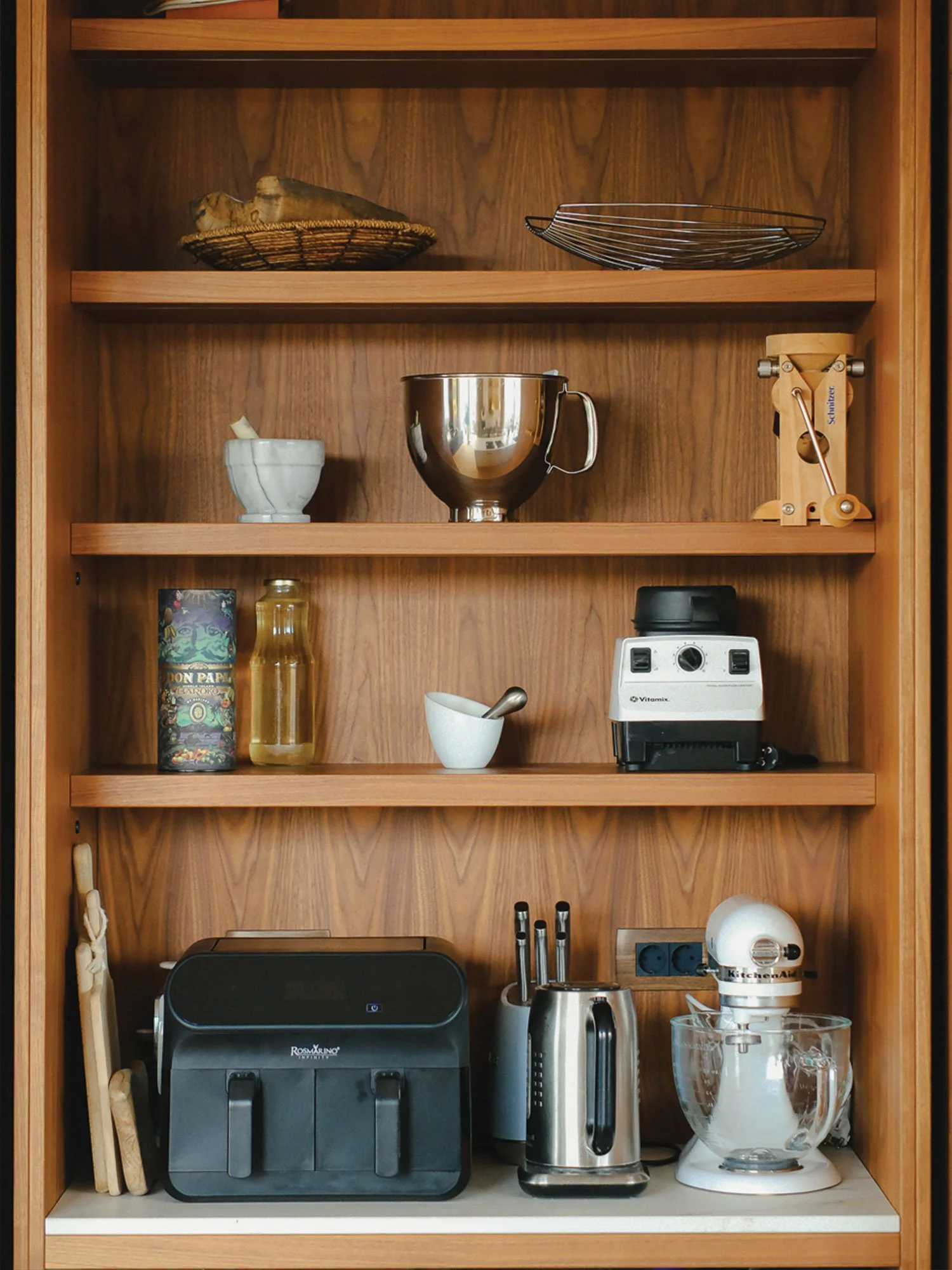 Shranjevanje v kuhinji z odprtimi policami iz temnega lesa.