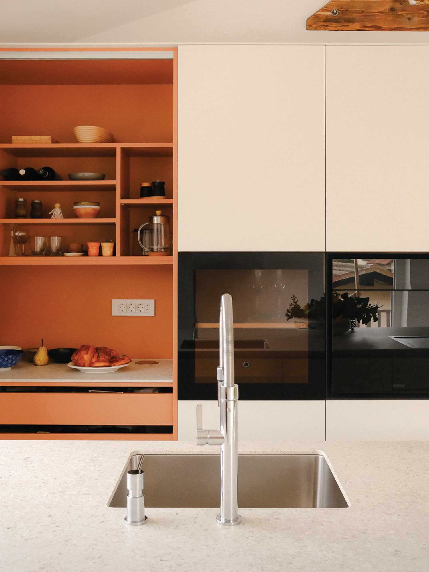 Nevtralna bež kuhinja z oranžno notranjostjo in kuhinjo v kuhinji.