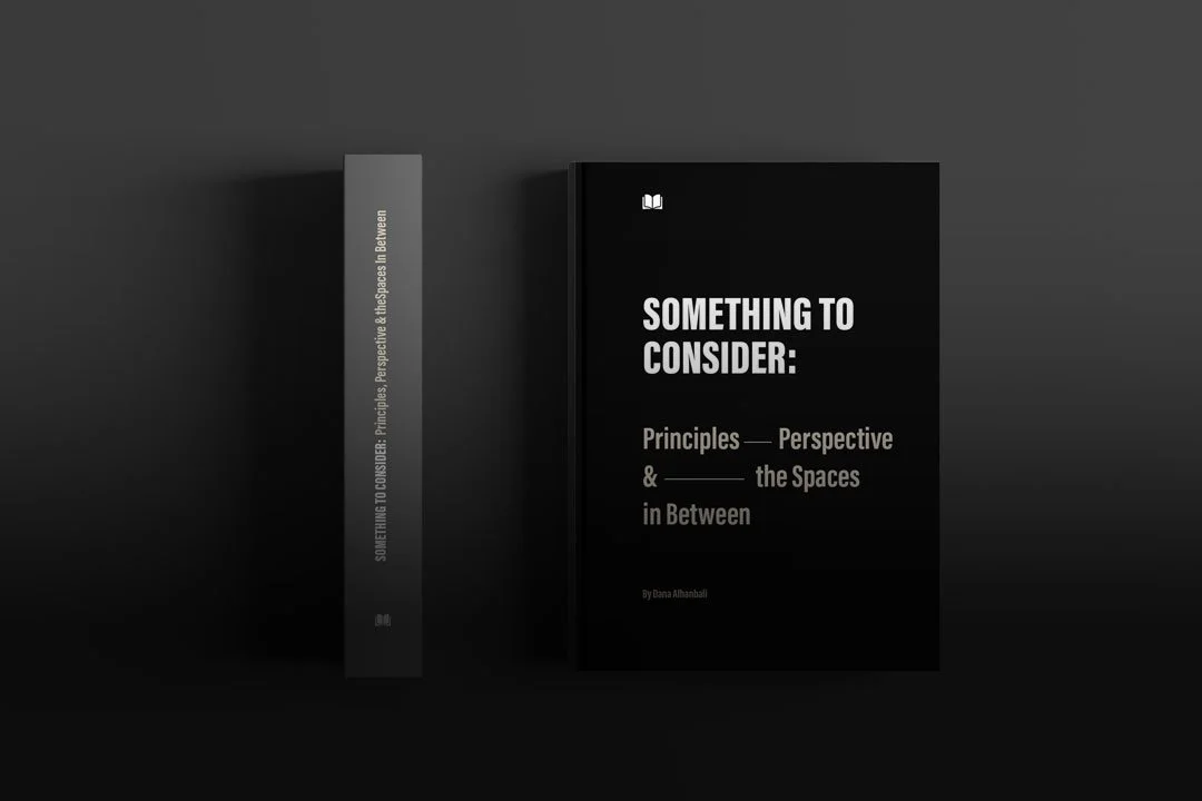 A black book titled 'SOMETHING TO CONSIDER: Principles, Perspective & the Spaces in Between' by Dana Alhanball, displayed upright next to its spine on a dark background with a shadow.
