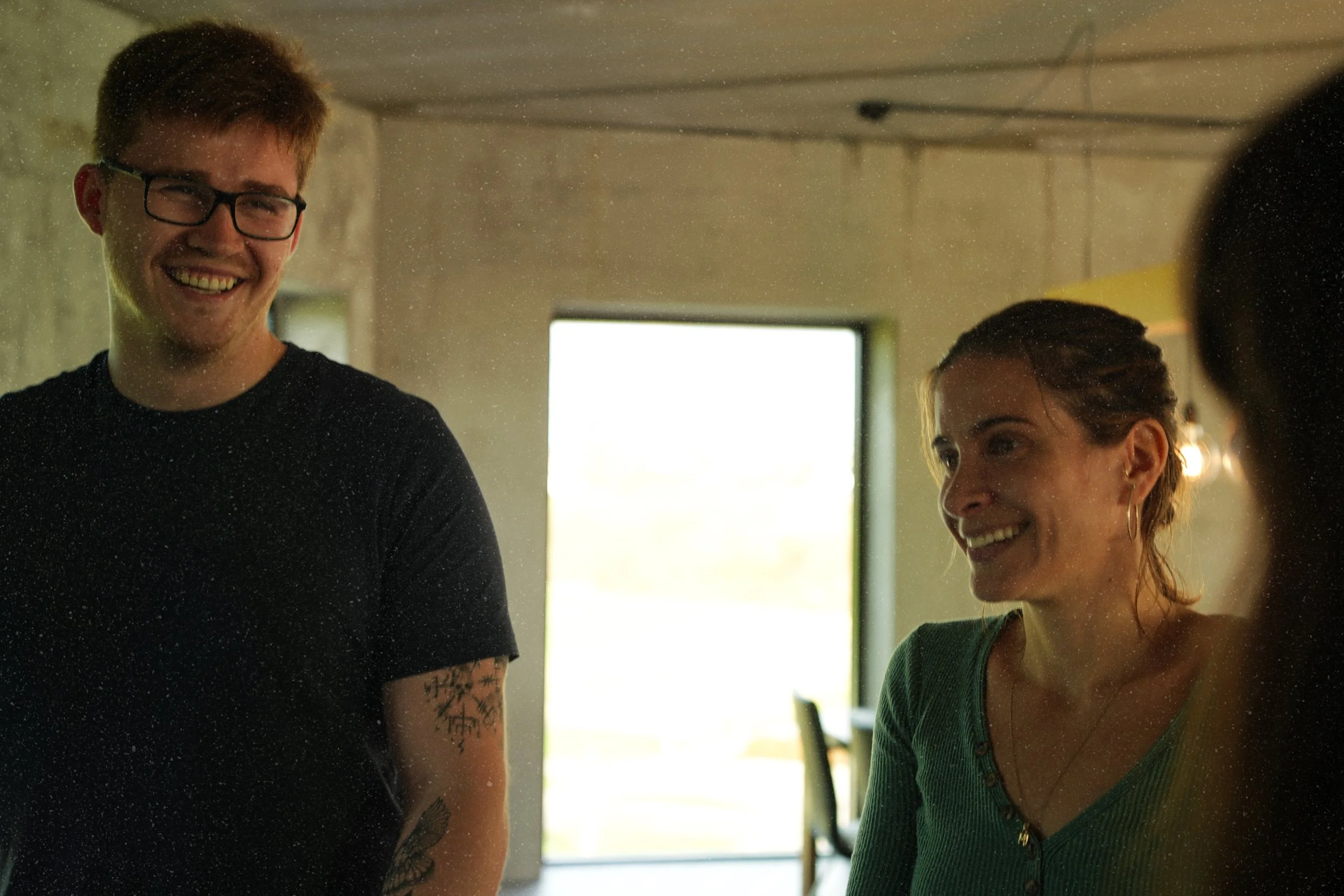 To mennesker som smiler og ler i en rom med naturlig lys, slapper av og har det gøy.