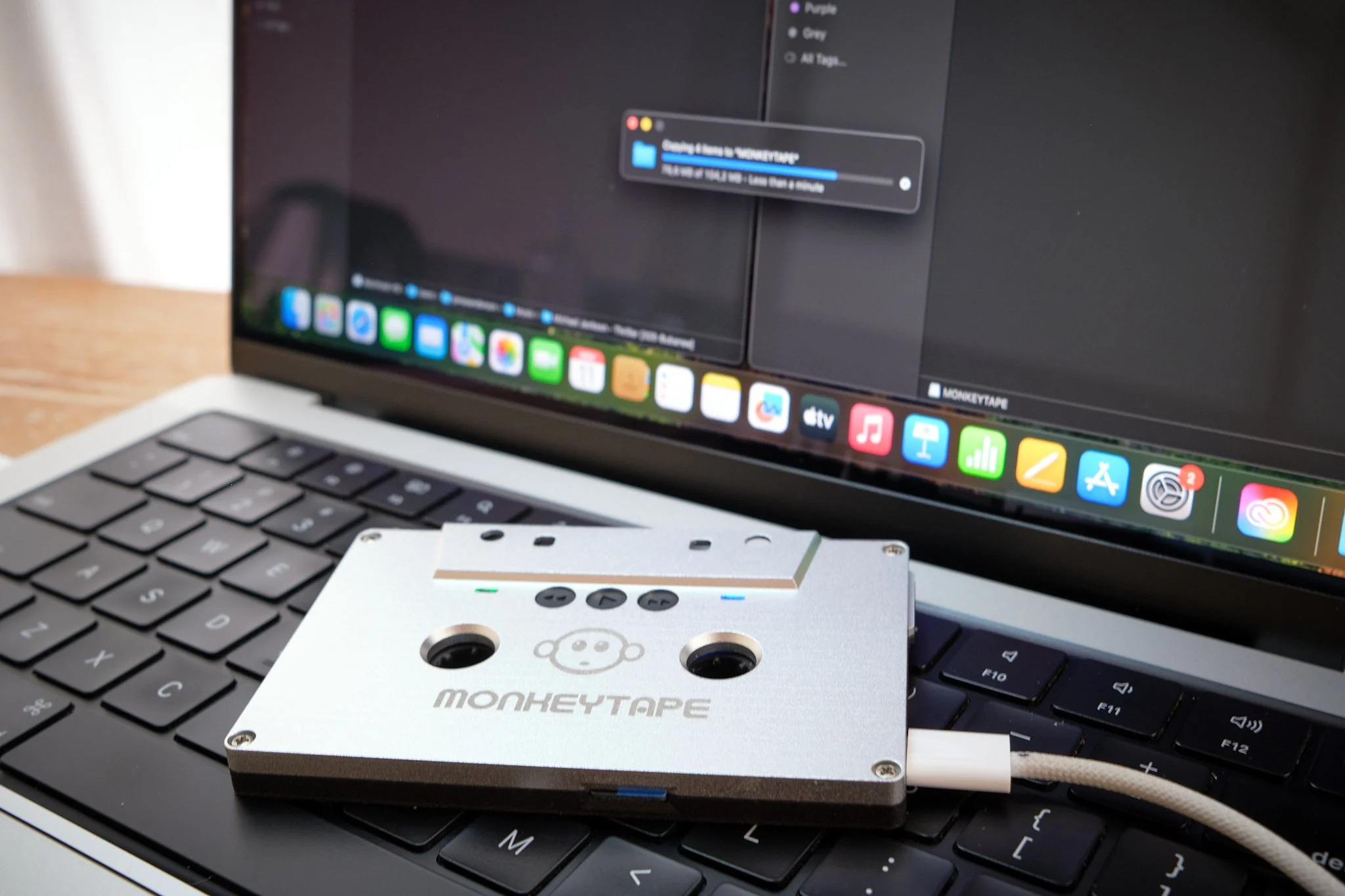 A digital audio mixer or interface connected to a laptop on a wooden desk.