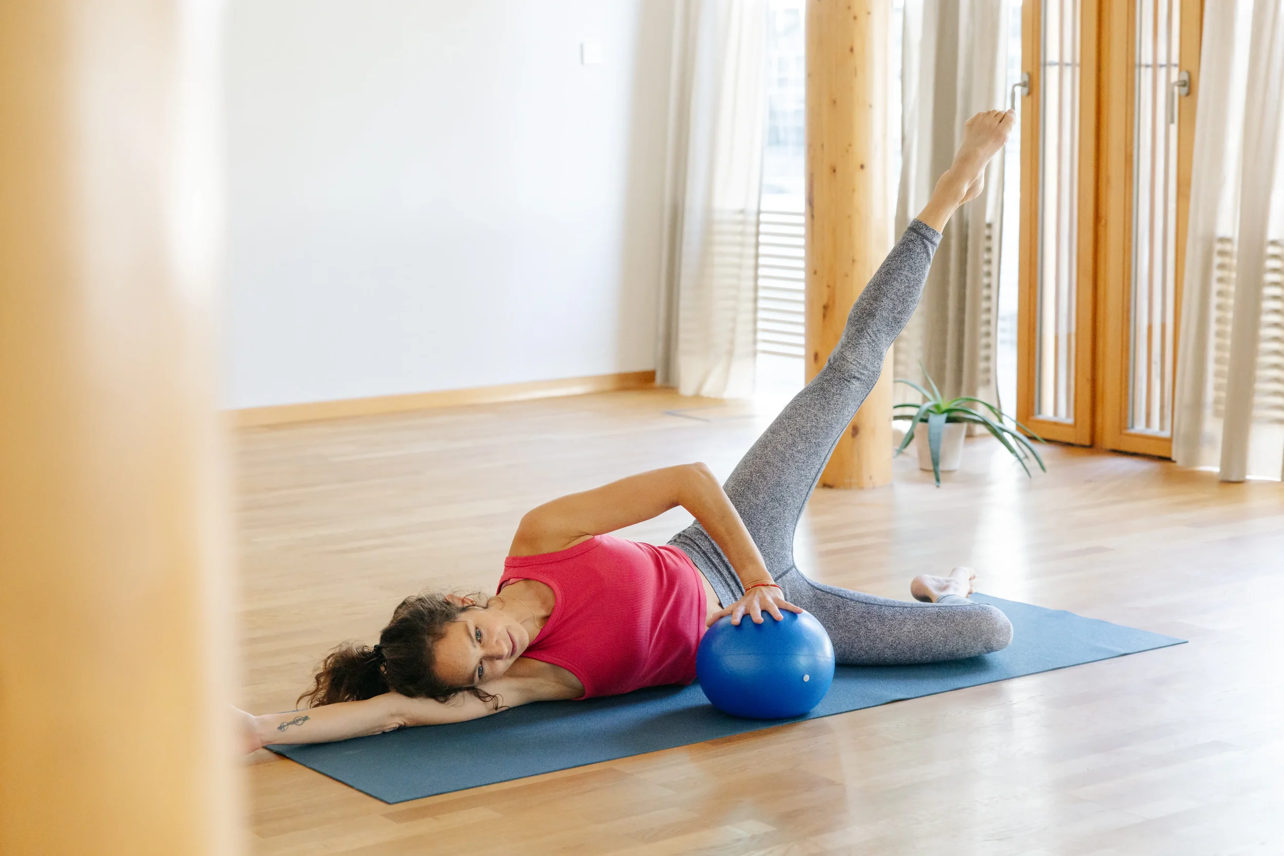 Frau beim Rückbildungstraining mit einem weichen Ball im Yogaraum in Interlaken. Achtsame Bewegung für Beckenboden und Körpermitte im MindfulMama Kurs.