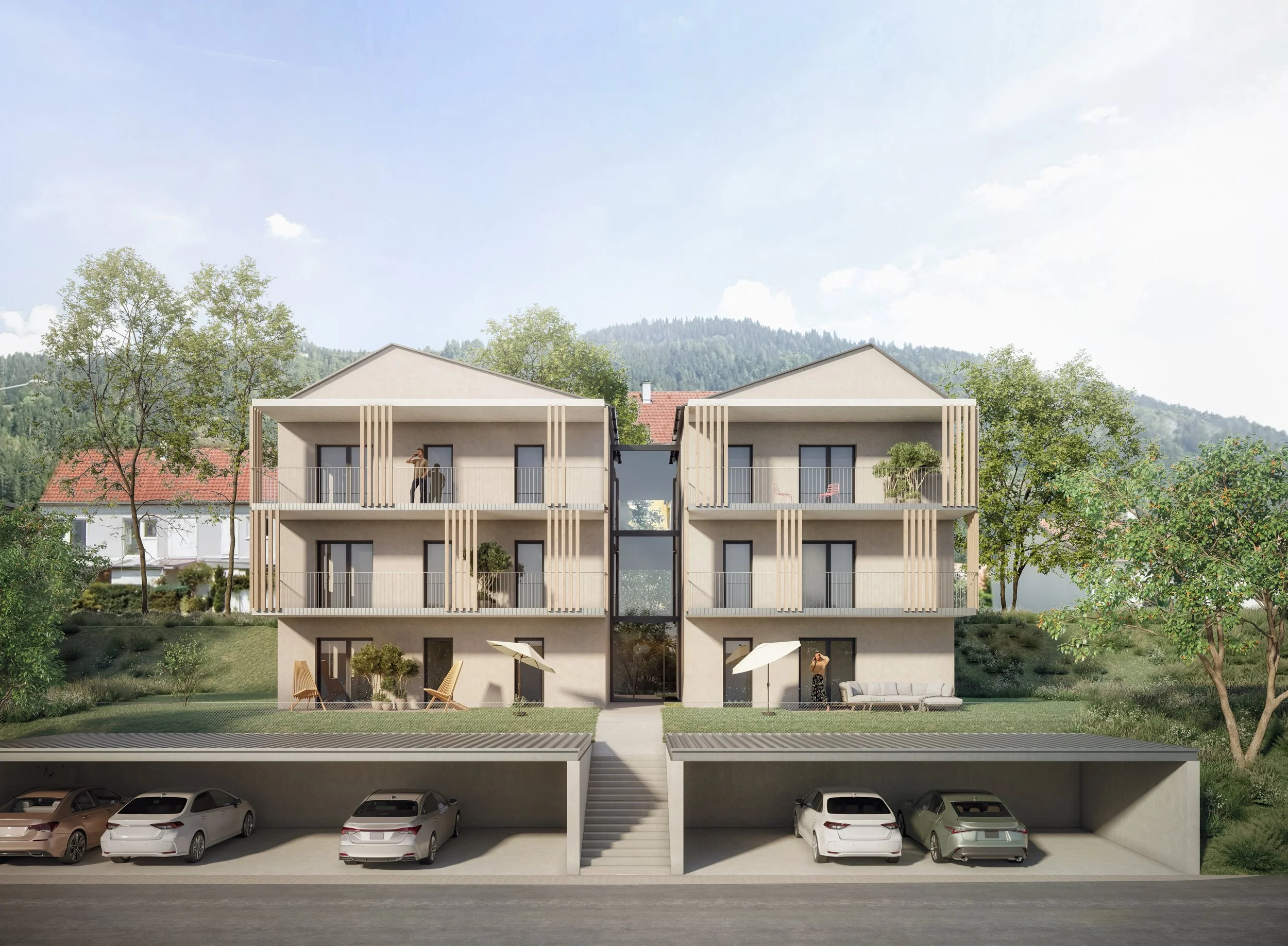Modern multi-story residential building with garage and parking area in front, surrounded by greenery and trees, with mountains and blue sky in the background.