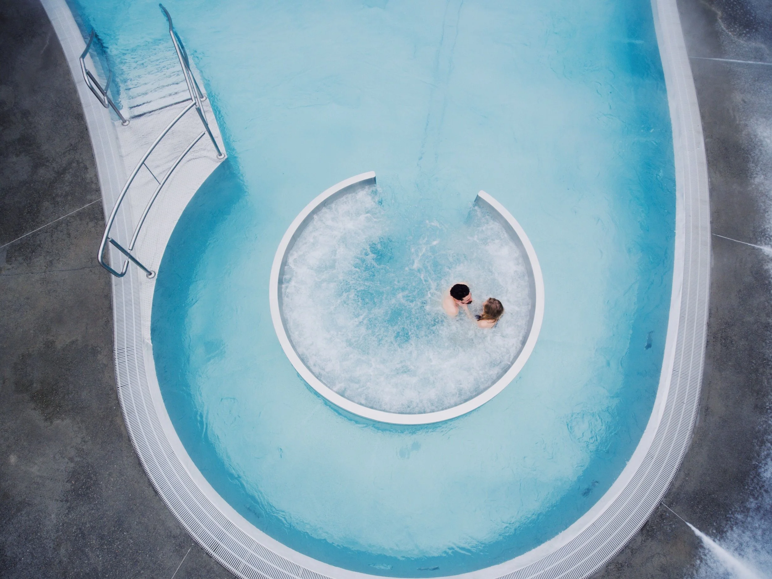 Deux personnes nageant dans une piscine en forme de cercle, vue de haut.