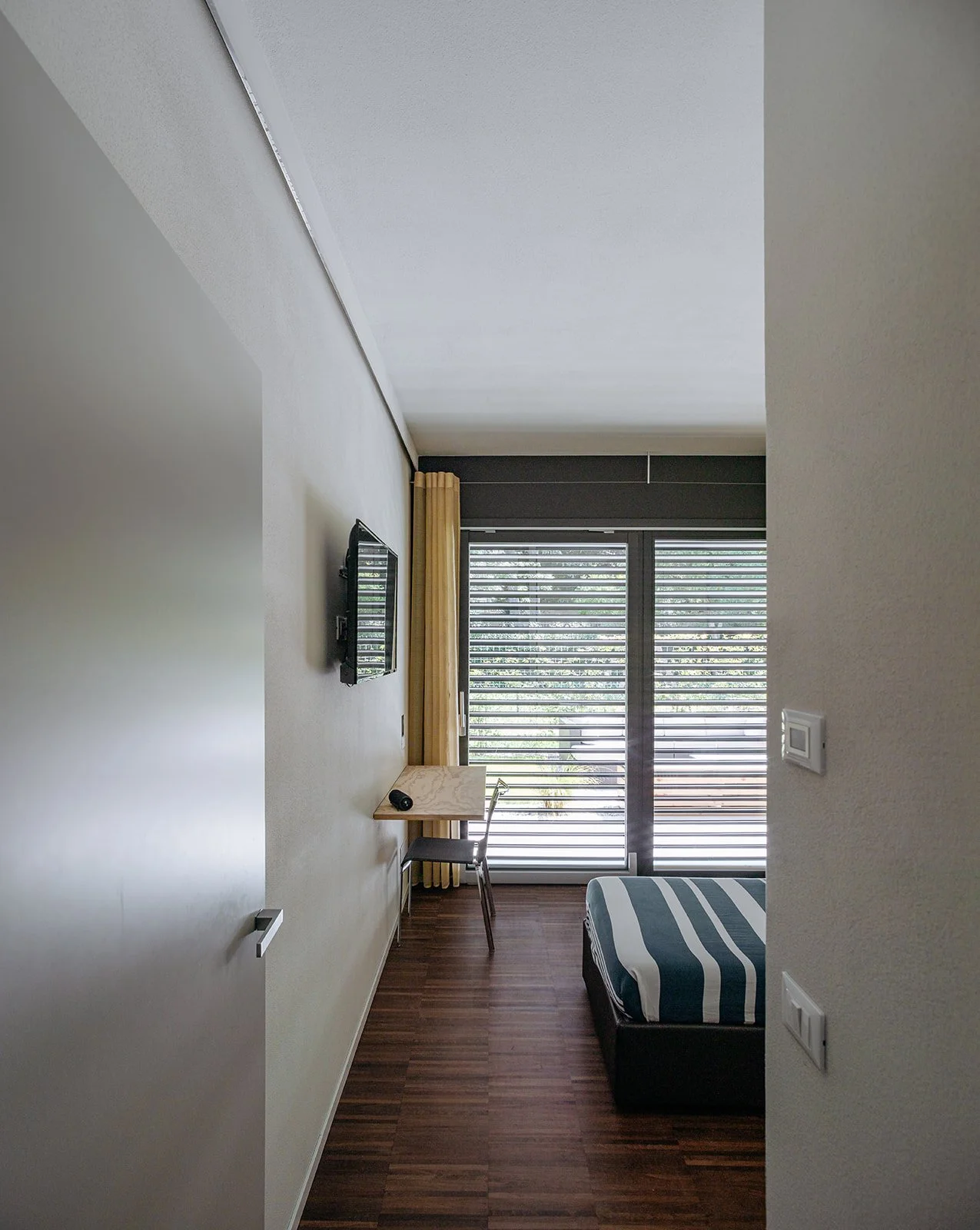 Camera dal design minimal e luminoso con arredi su misura e parquet in legno. Interno progettato da DAT Architetti.