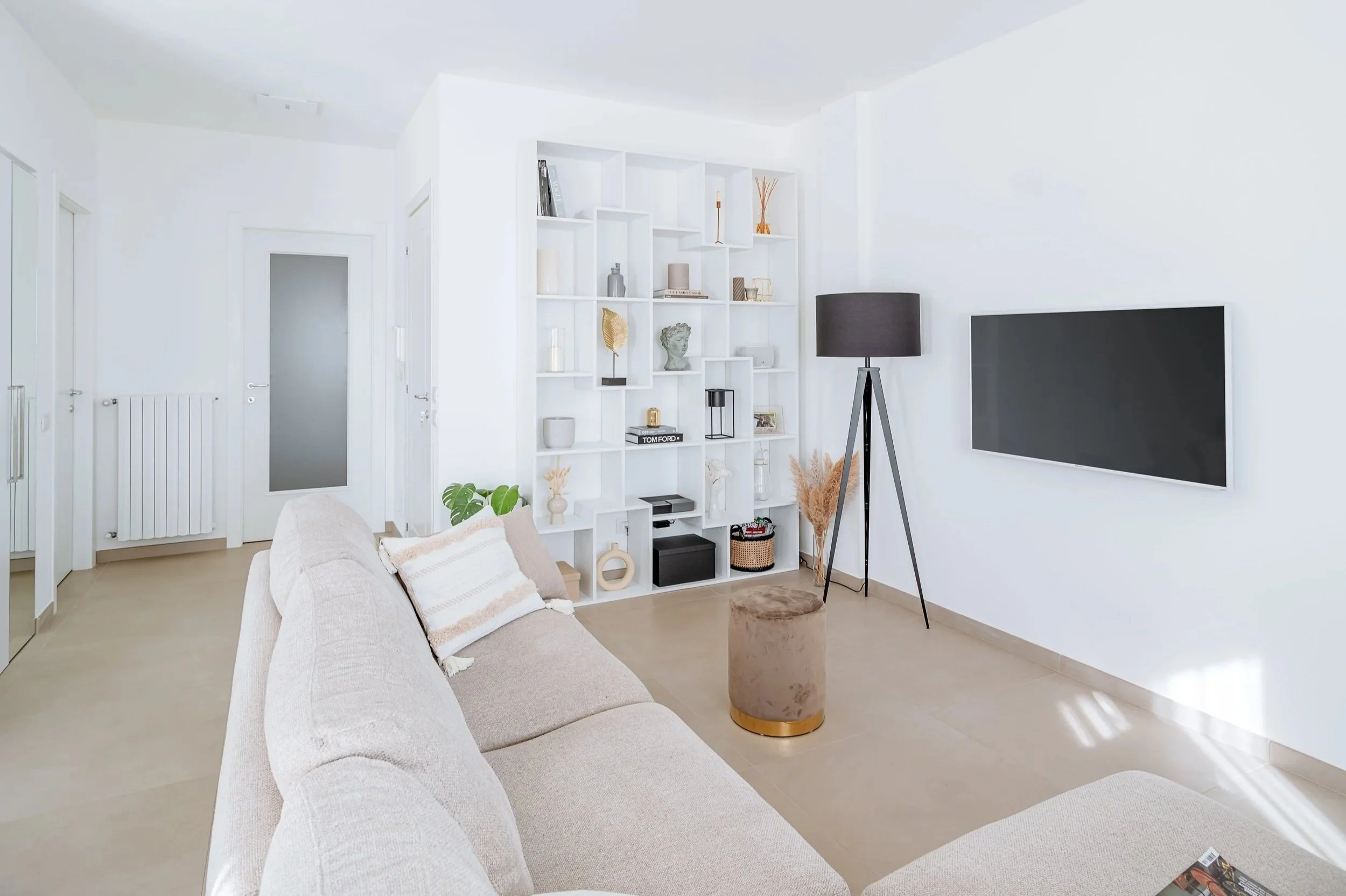 Soggiorno con divano e libreria bianca minimalista.