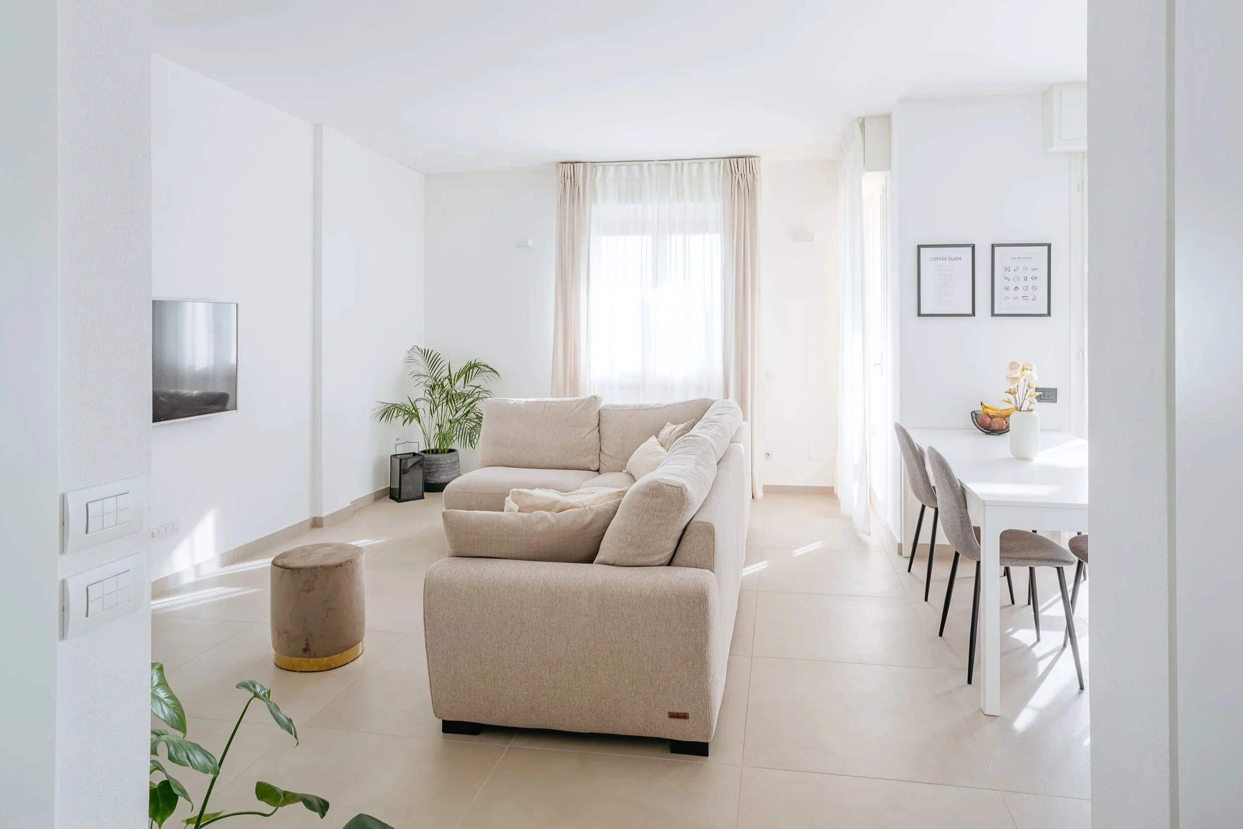 Zona giorno con divano e tavolo da pranzo in appartamento luminoso.